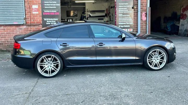 A grey Audi S5 Sportback with its chrome window surrounds blacked out