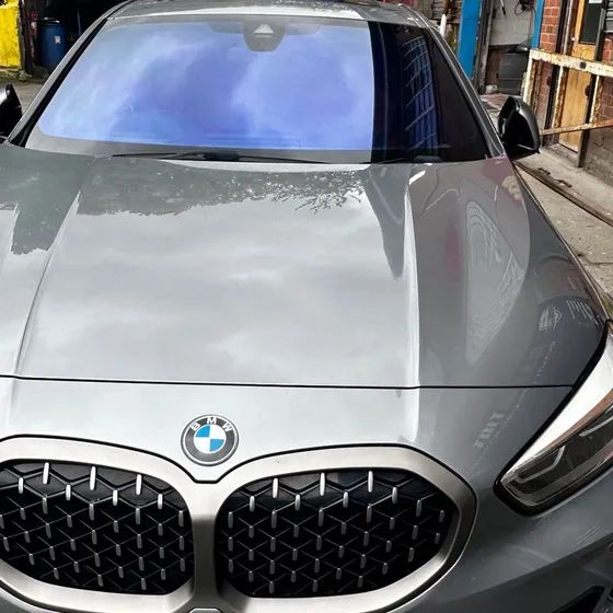 A grey BMW 1 Series with a chameleon windscreen