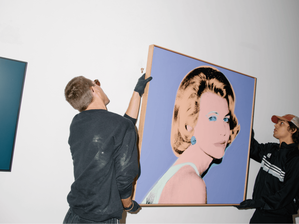 Two men hanging a painting