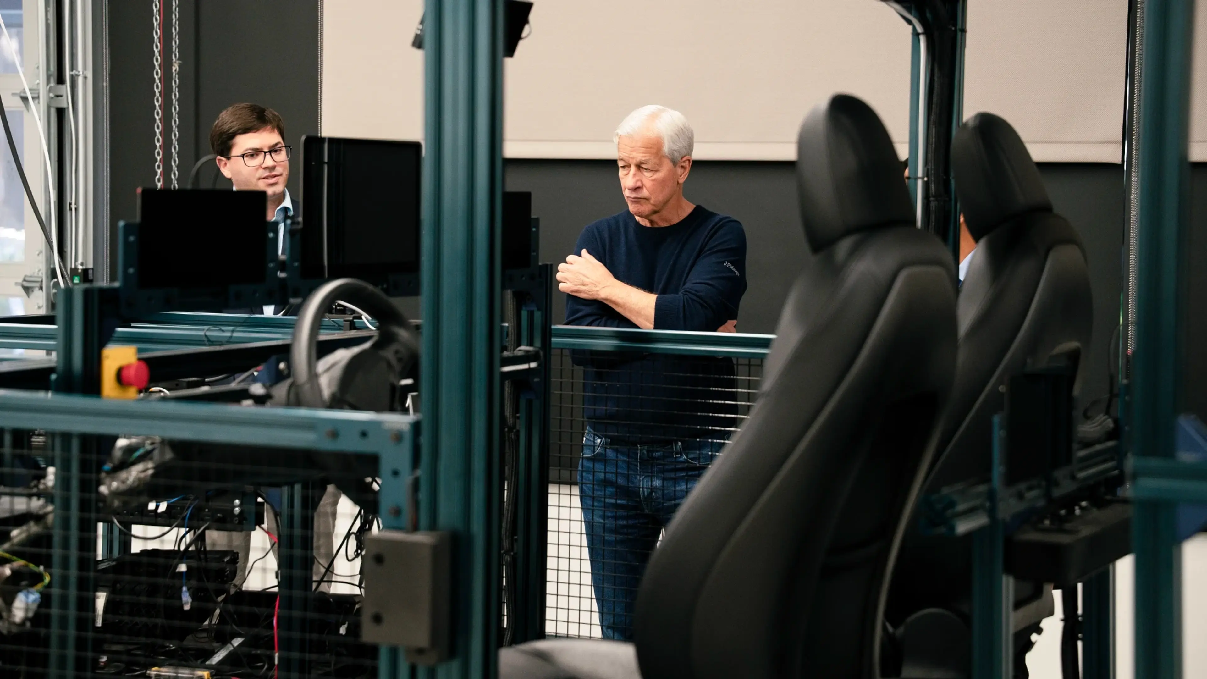 Executives reviewing a vehicle simulator rig inside a test facility