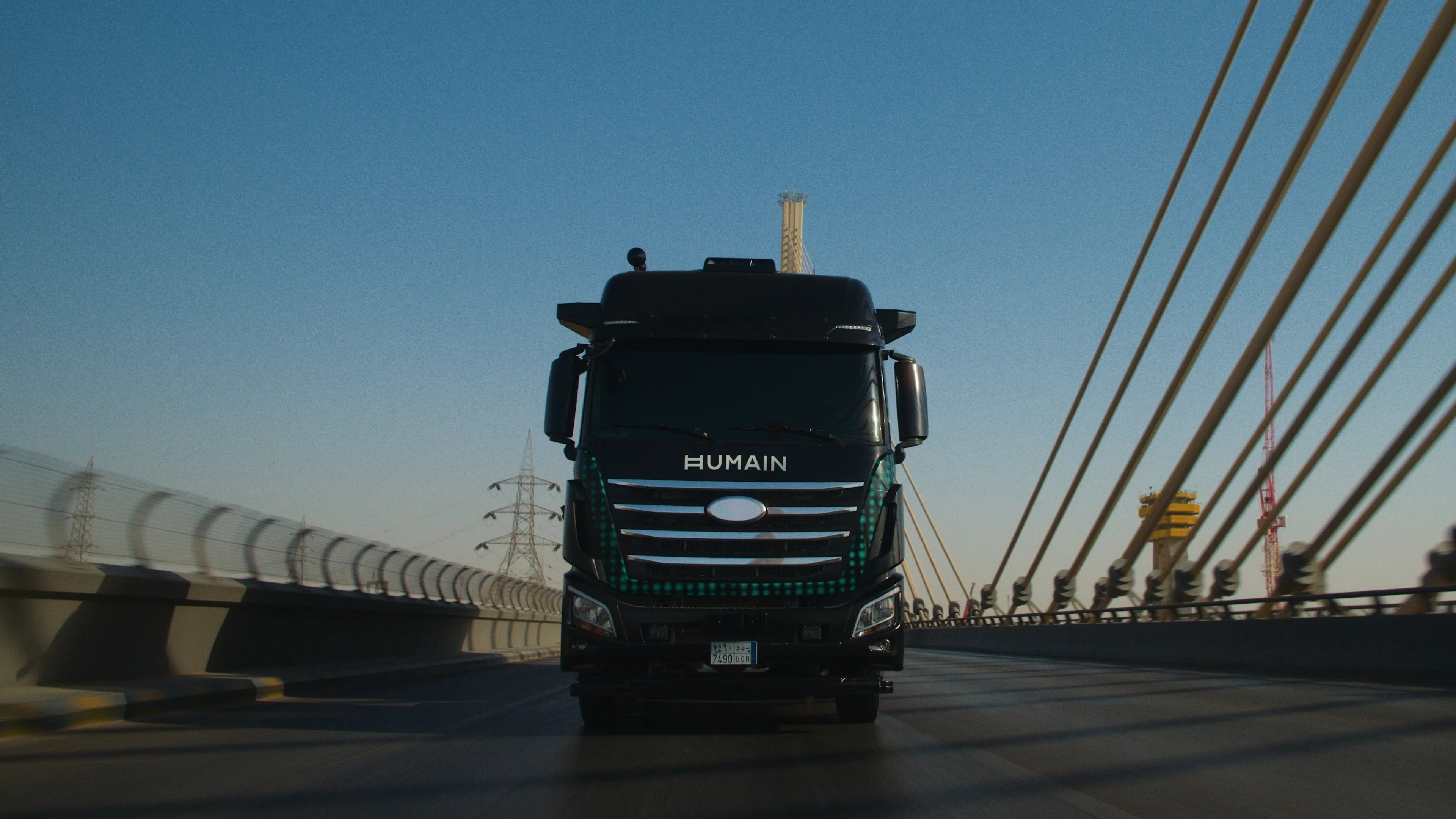 HUMAIN-branded black autonomous truck crossing a cable-stayed bridge.