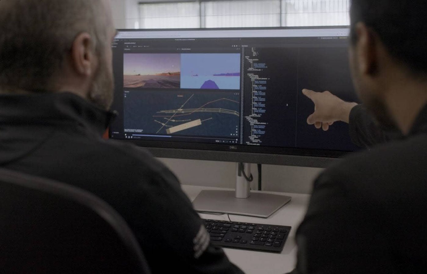 Two engineers reviewing a simulated scene on a monitor