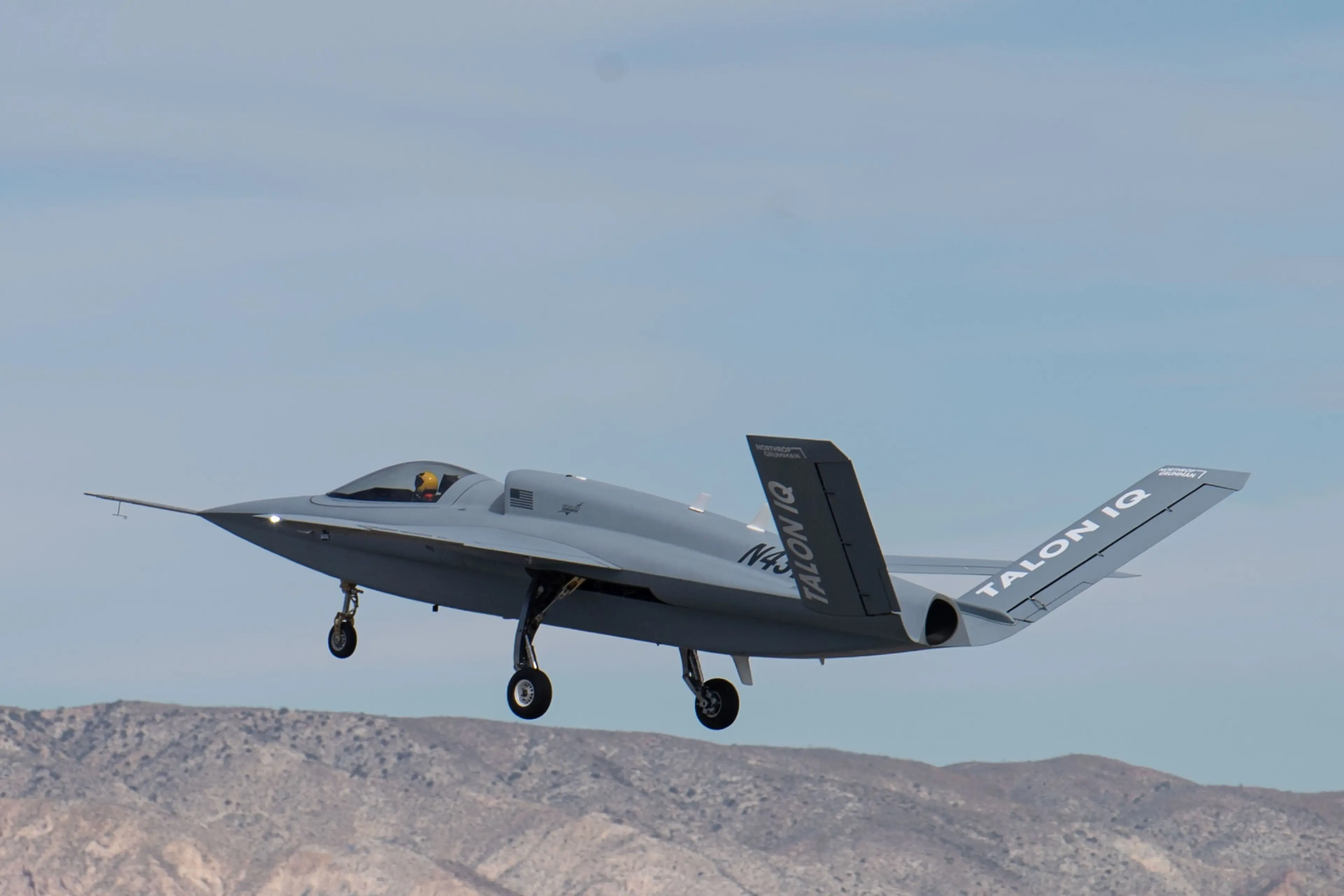 Northrop Grumman Talon IQ experimental aircraft taking off from a desert airstrip, with mountains in the background