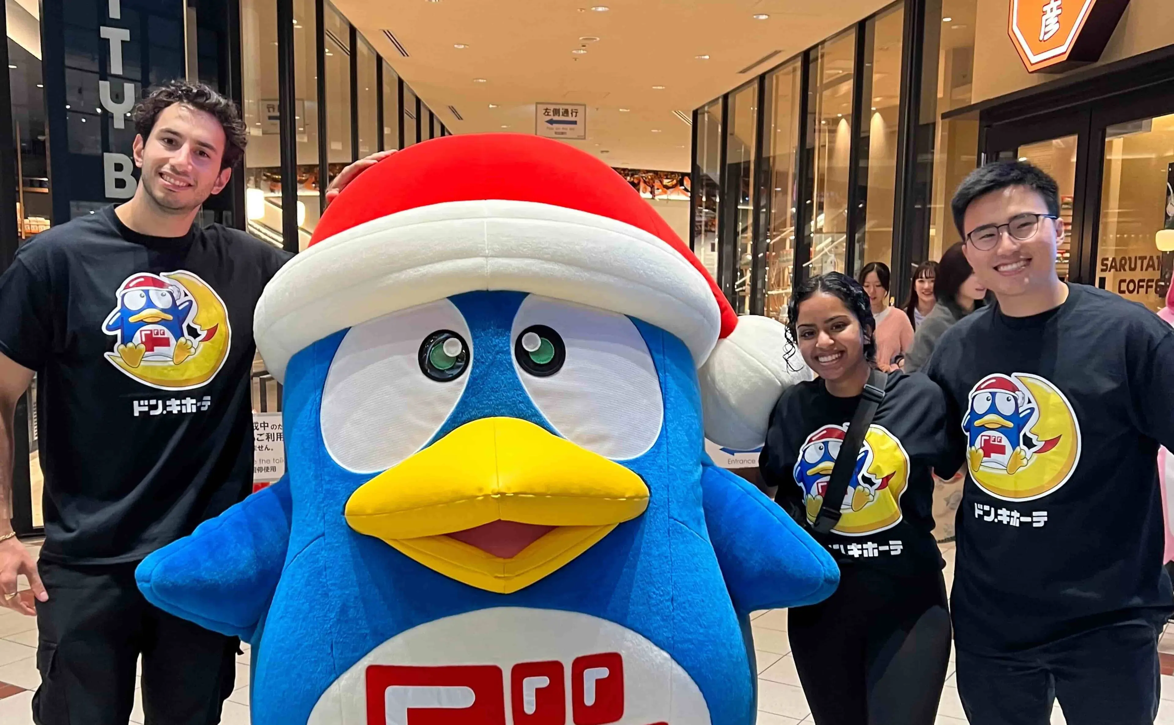From left, Daniel Jabbour, Deepshika Dhanasekar, and Micah Yong make a new friend at Don Quijote, a Japanese retail store.