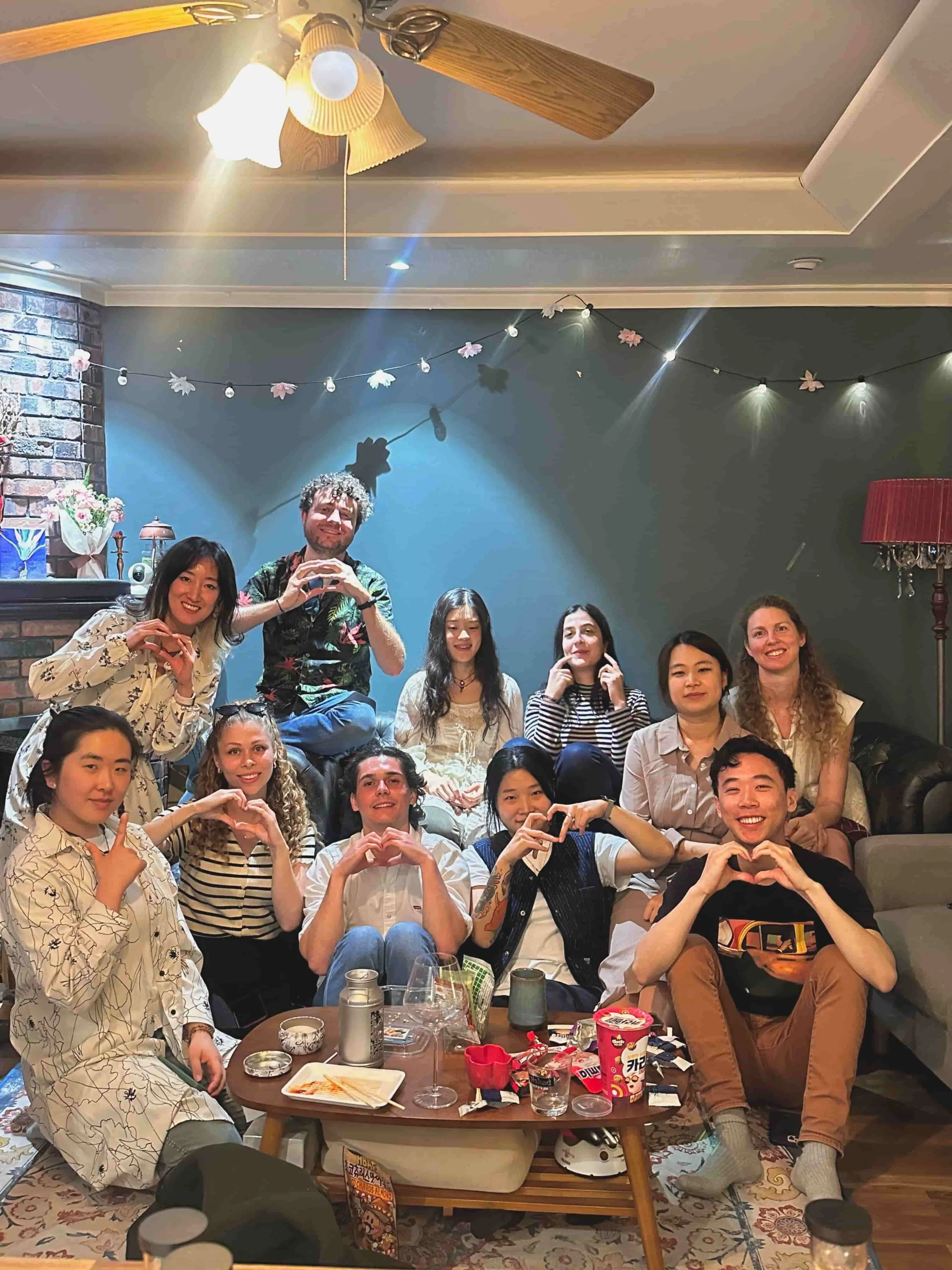 Group of eleven people making heart gestures - Kevin Li (front right) after a "family dinner" in his Seoul co-living house