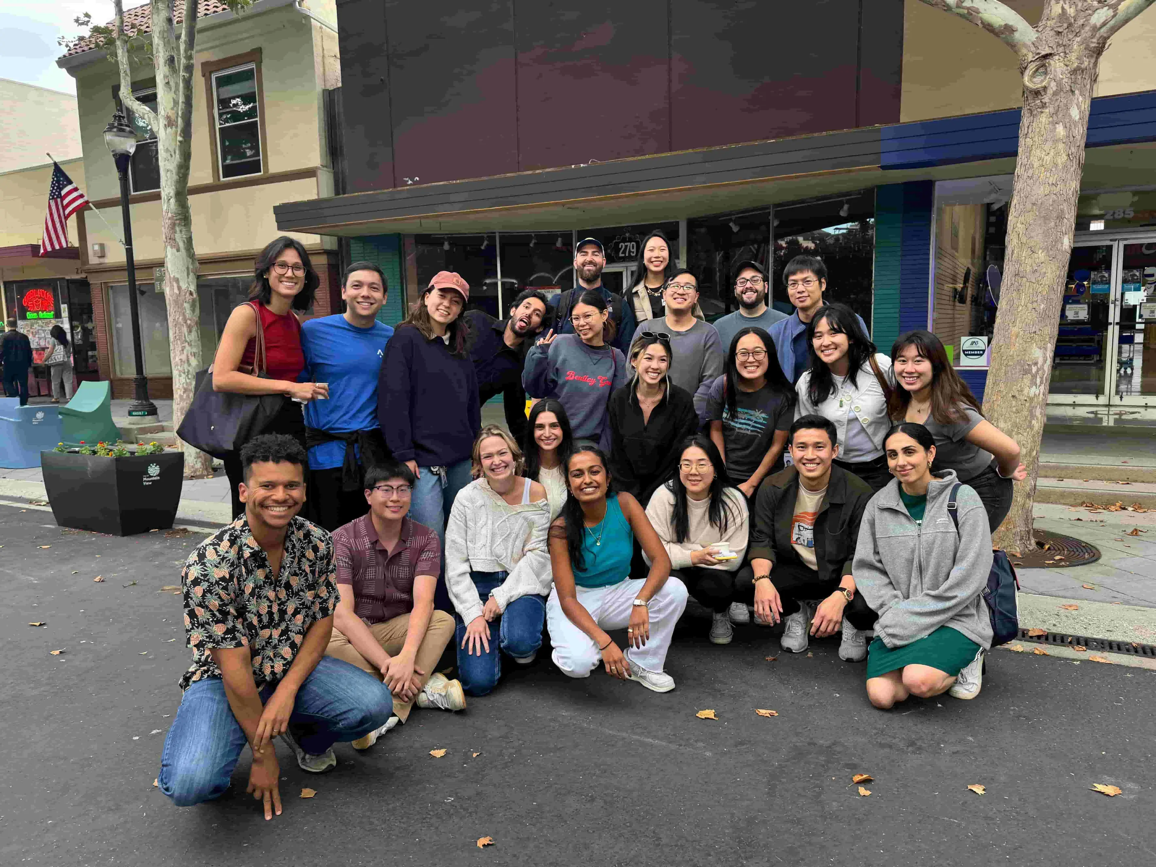 About 20 people posing for a photo on a street