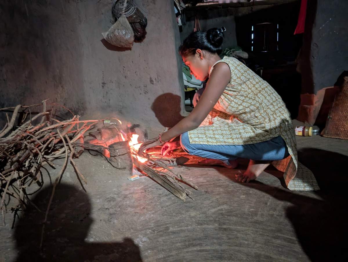 Without access to grid electricity and with solar batteries fully drained,Manjita devi relies on a traditional hearth to cook in the dark. Photographed with auxiliary lighting.