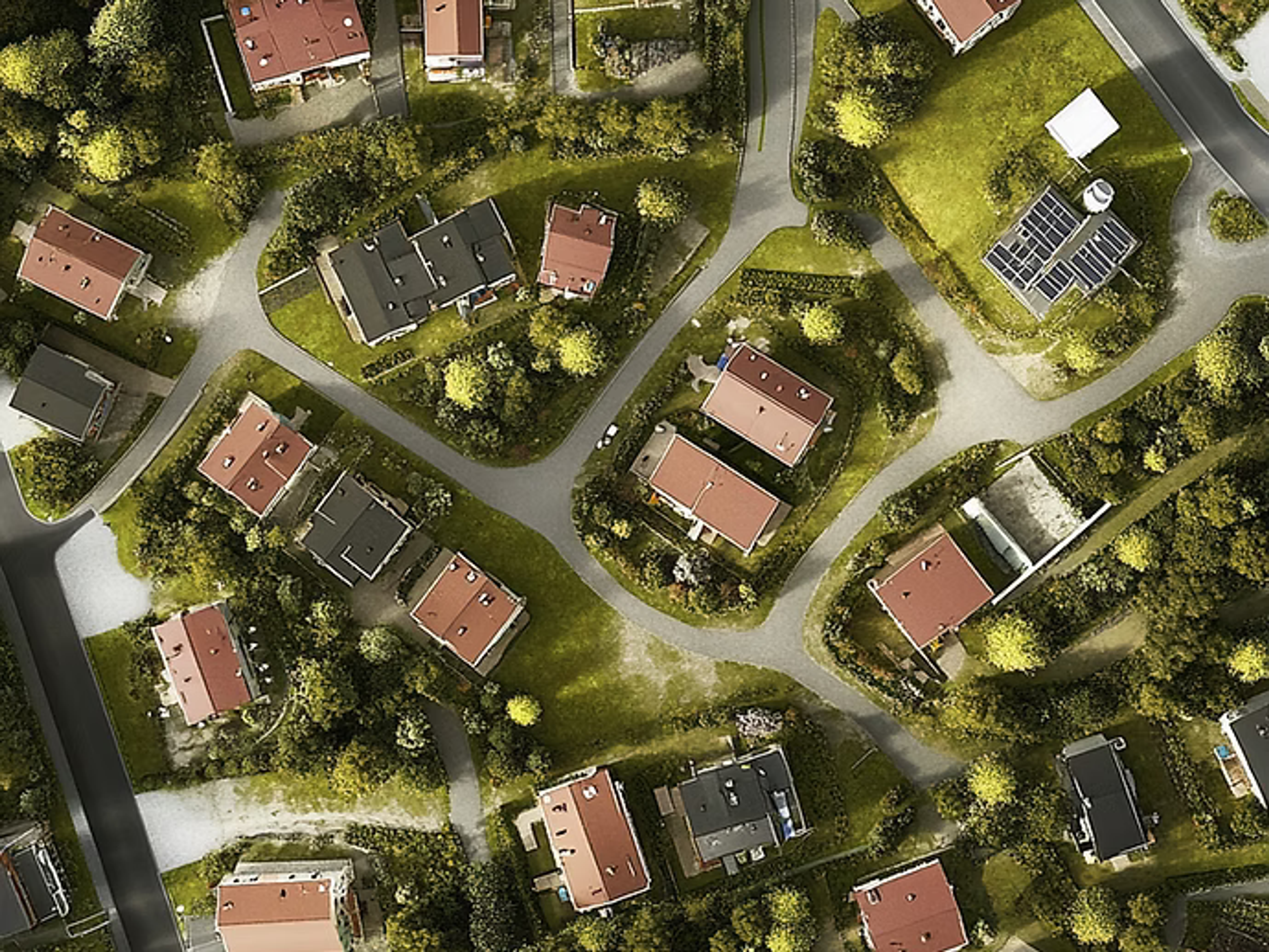 Flygbild över ett villaområde med rödmålade hus, vägar och grönska