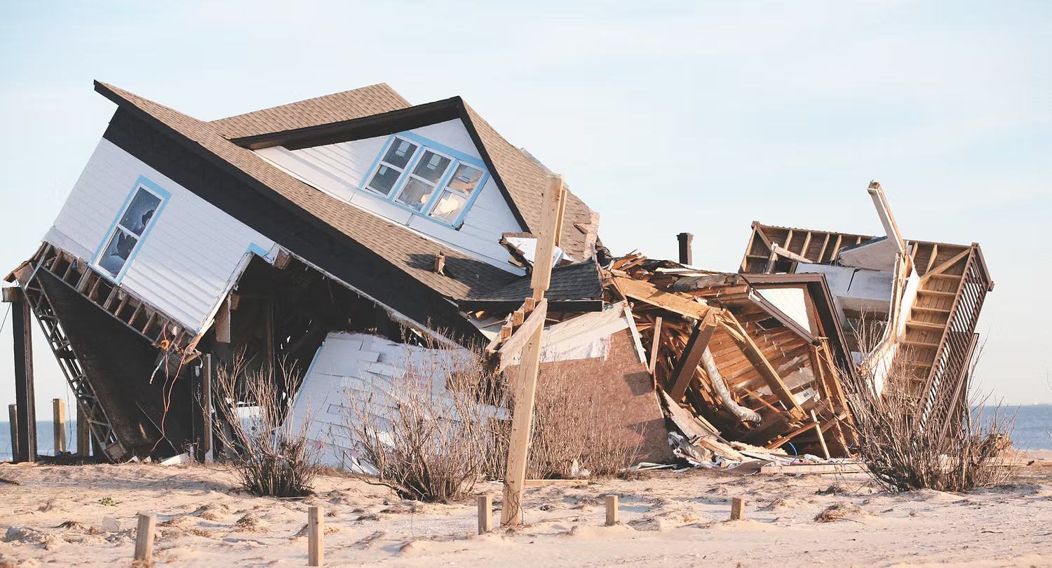 Kollapsat trähus liggande skadat på en strand efter storm