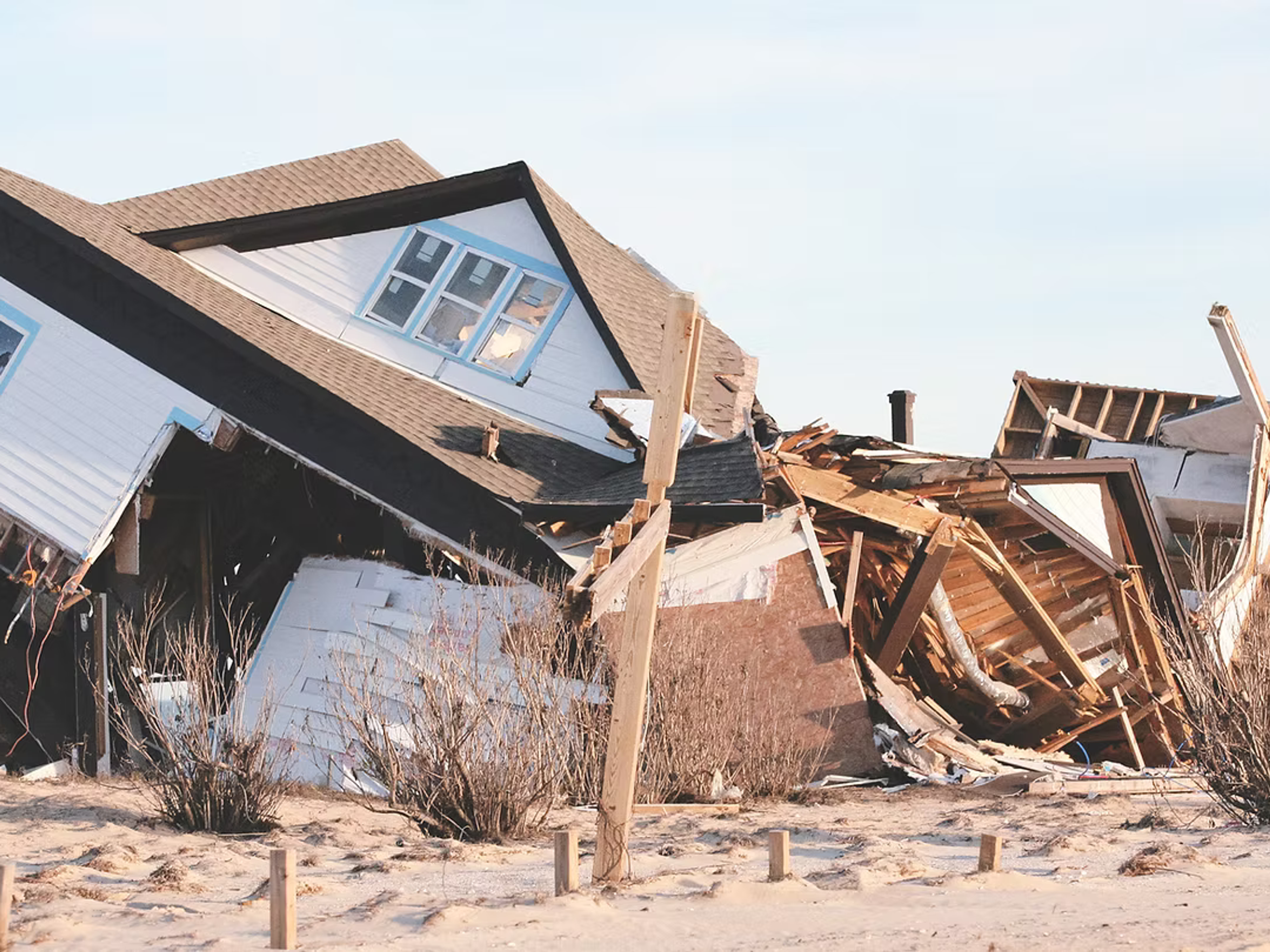 Kollapsat trähus liggande skadat på en strand efter storm