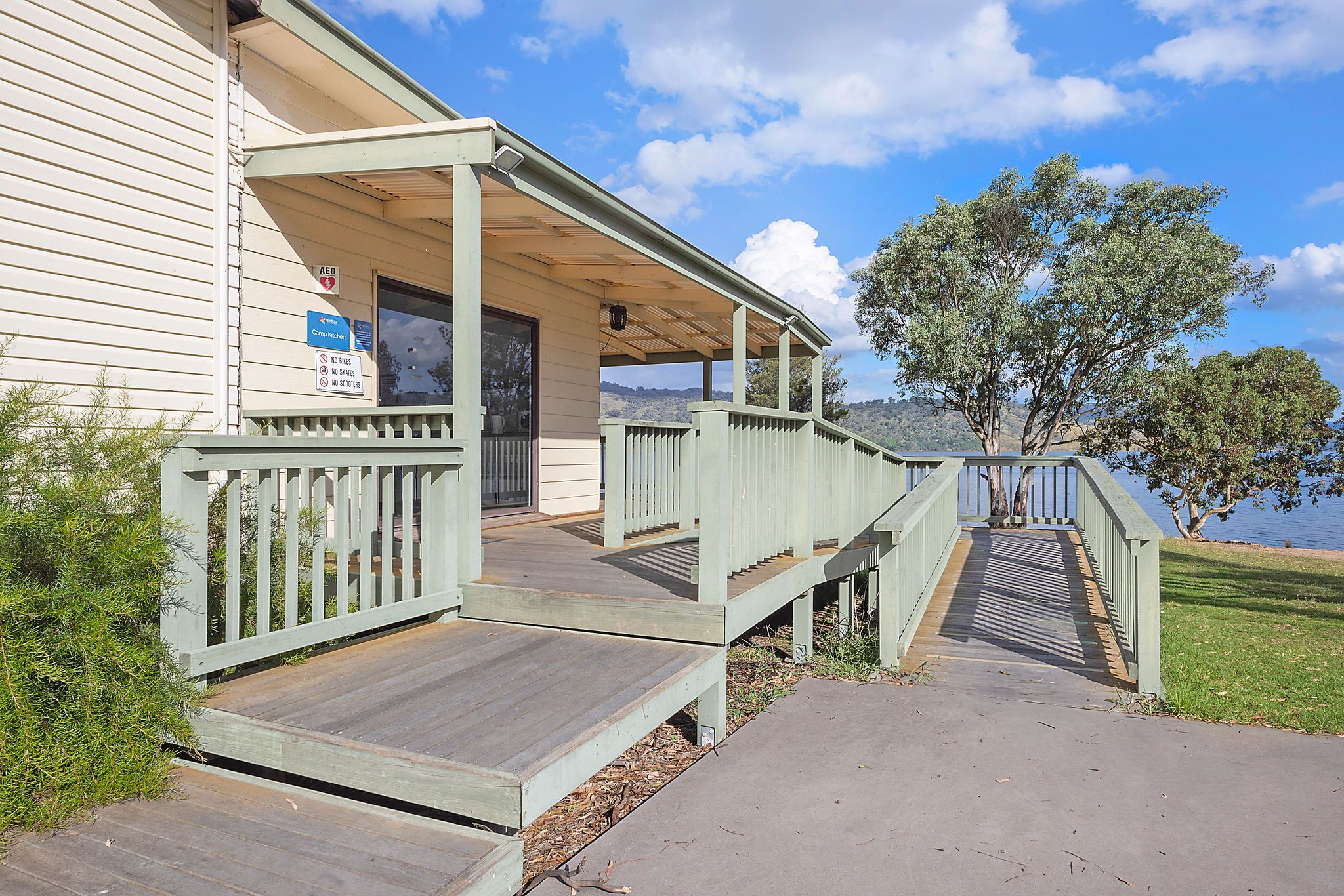 Accessible ramp leading to the entrance of the camp kitchen at Reflections Wyangala Waters, with lake views in the background