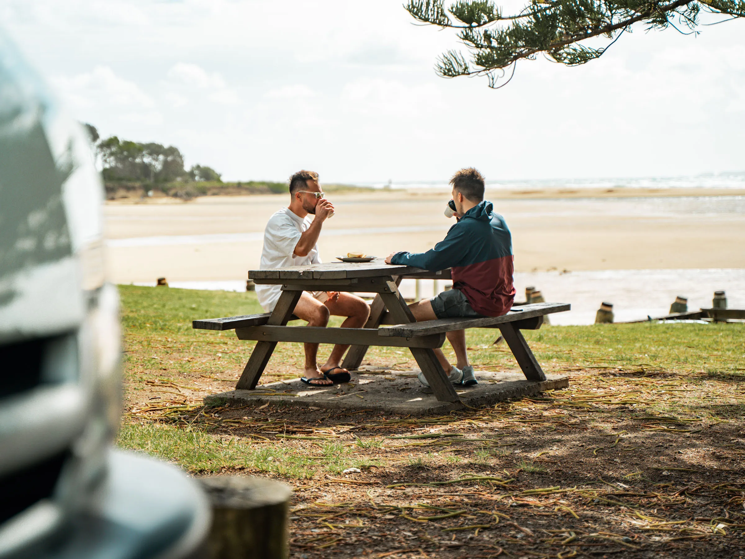 Reflections Moonee Beach holiday & caravan park men eating lunch at picknick table looking over the beach