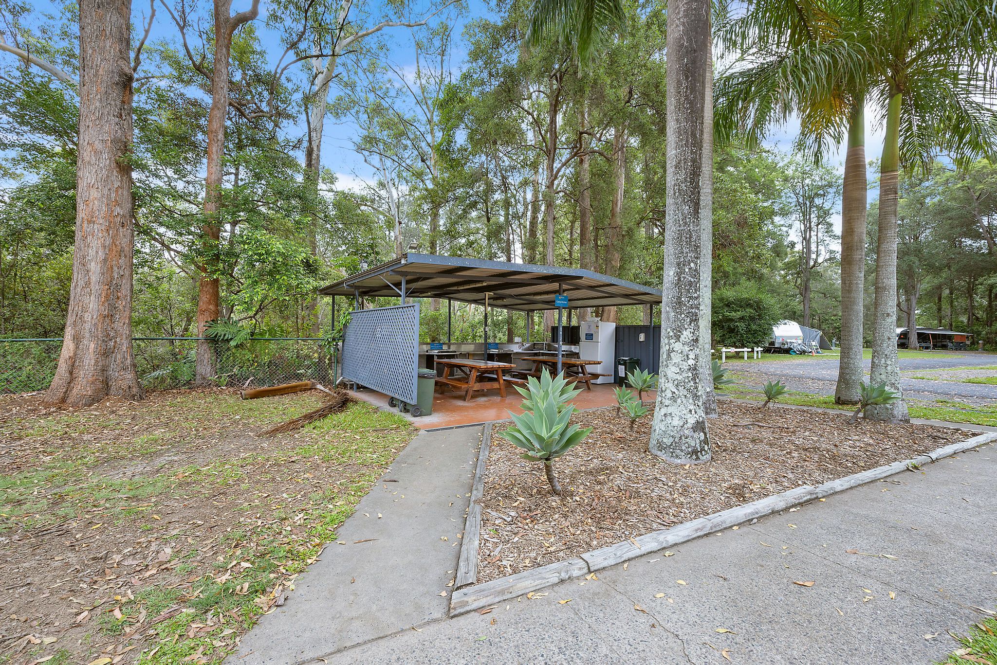 Reflections Holiday Park Coffs Harbour. – Outdoor camp kitchen area with benches and covered cooking facilities 