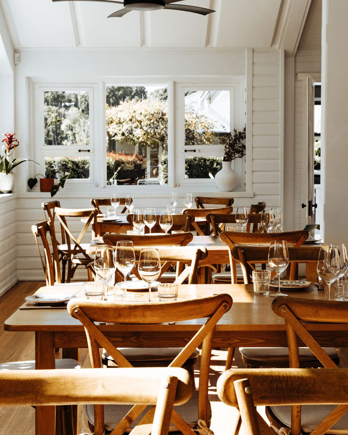 The Hut, Sunlit dining room with wooden tables and cross-back chairs 