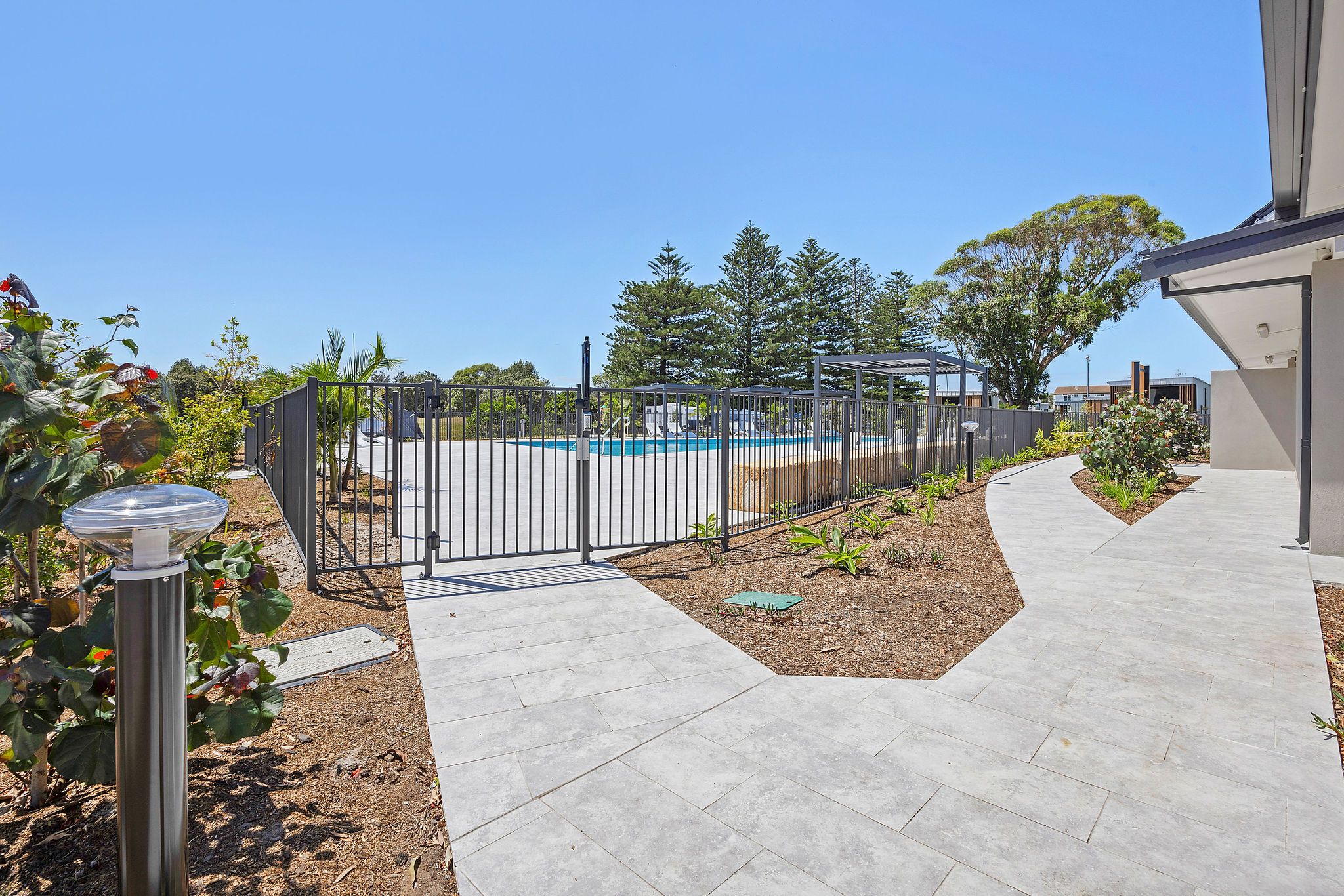 Gated entrance to the pool area at Reflections Hawks Nest, surrounded by pathways and greenery