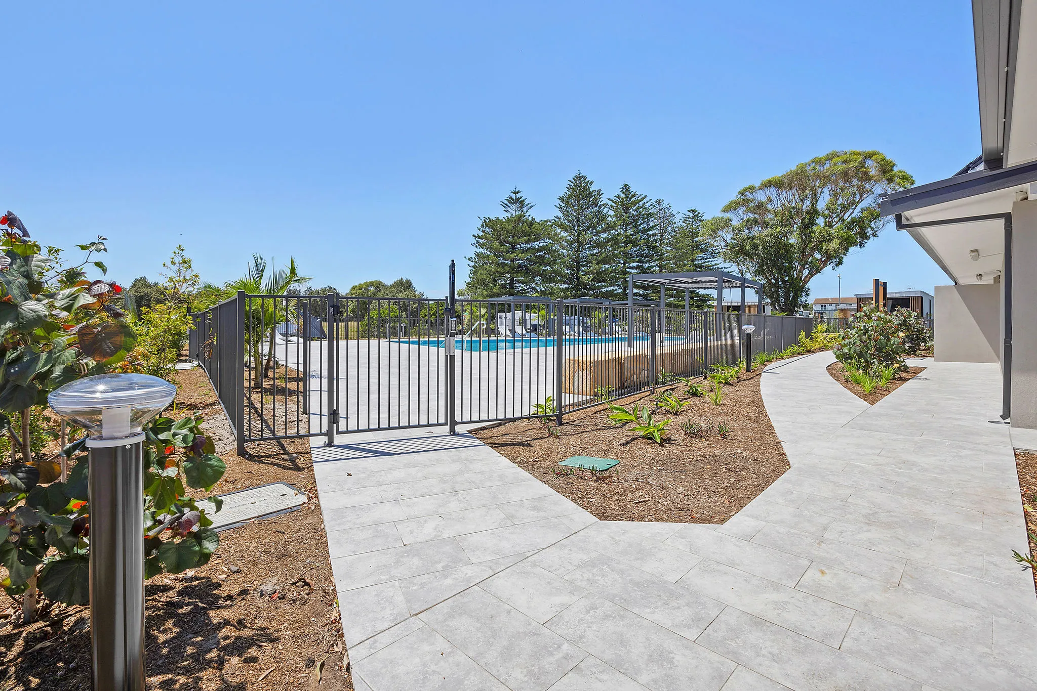 Gated entrance to the pool area at Reflections Hawks Nest, surrounded by pathways and greenery