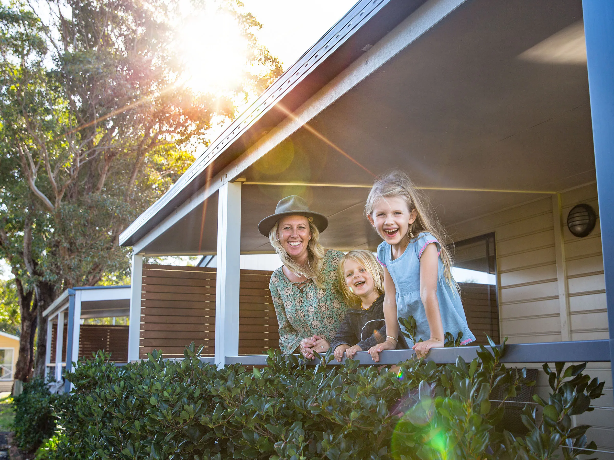 Reflections Holidays Hawks Nest holiday & caravan park family of three standing on cabin veranda