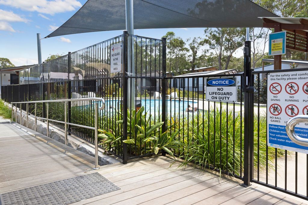 Fenced swimming pool area with shade sail at Reflections Jimmys Beach Caravan Park