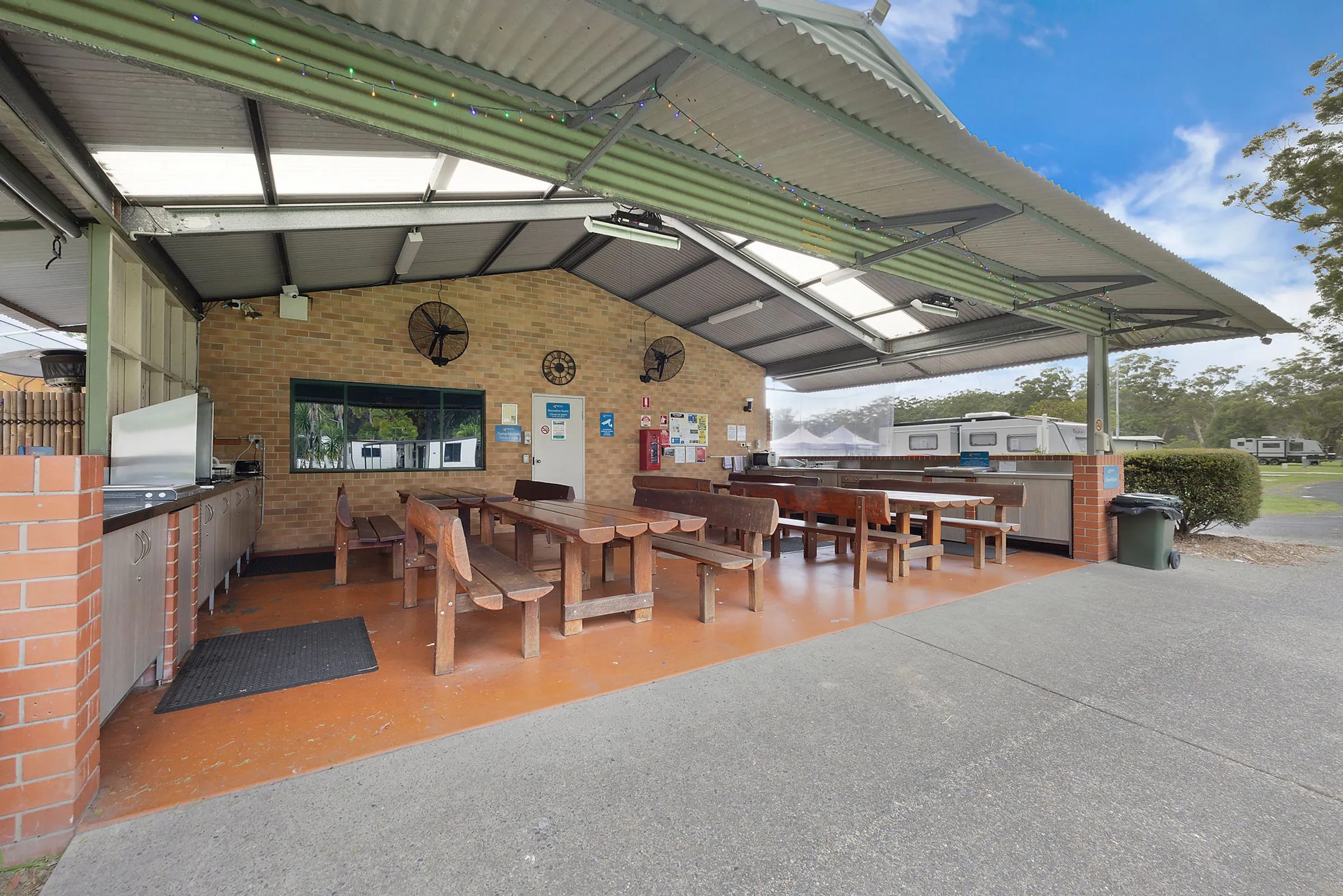 Reflections Holiday Park Coffs Harbour - Seating and dining area inside the covered camp kitchen with wooden benches