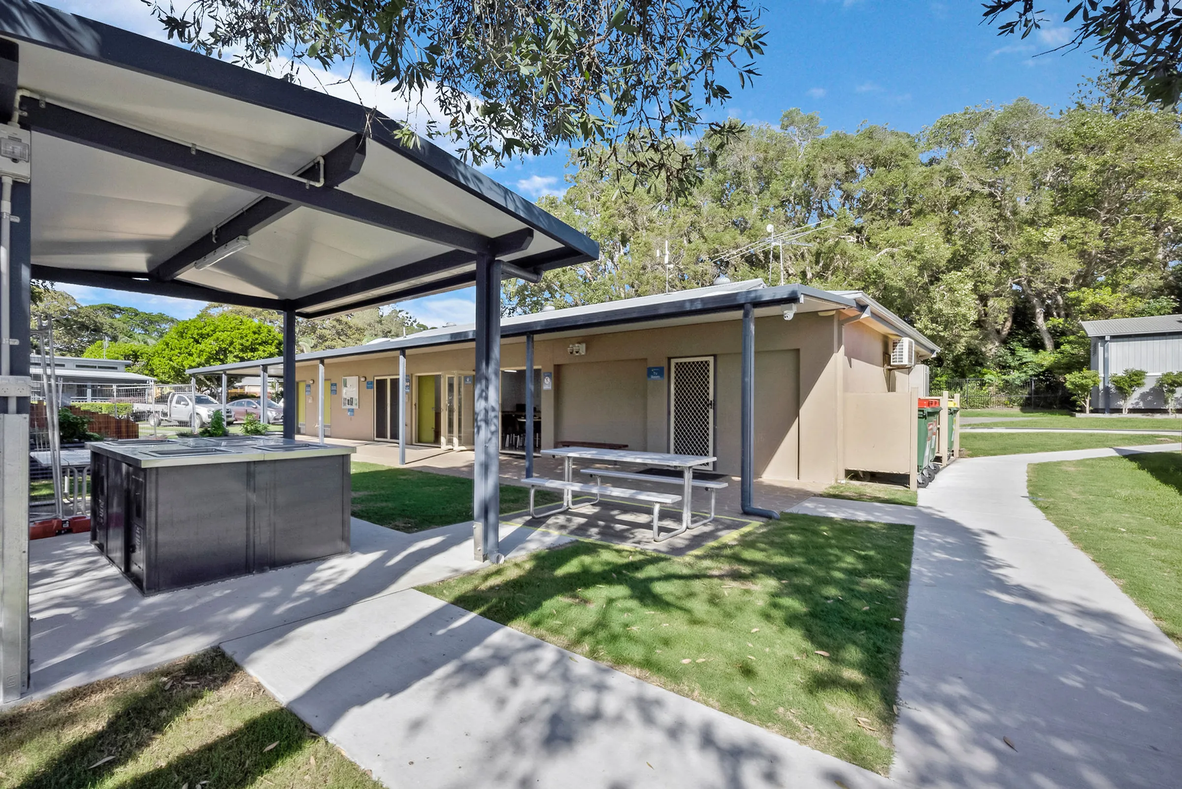 Outdoor BBQ area at Reflections Urunga with picnic tables and covered cooking facilities.