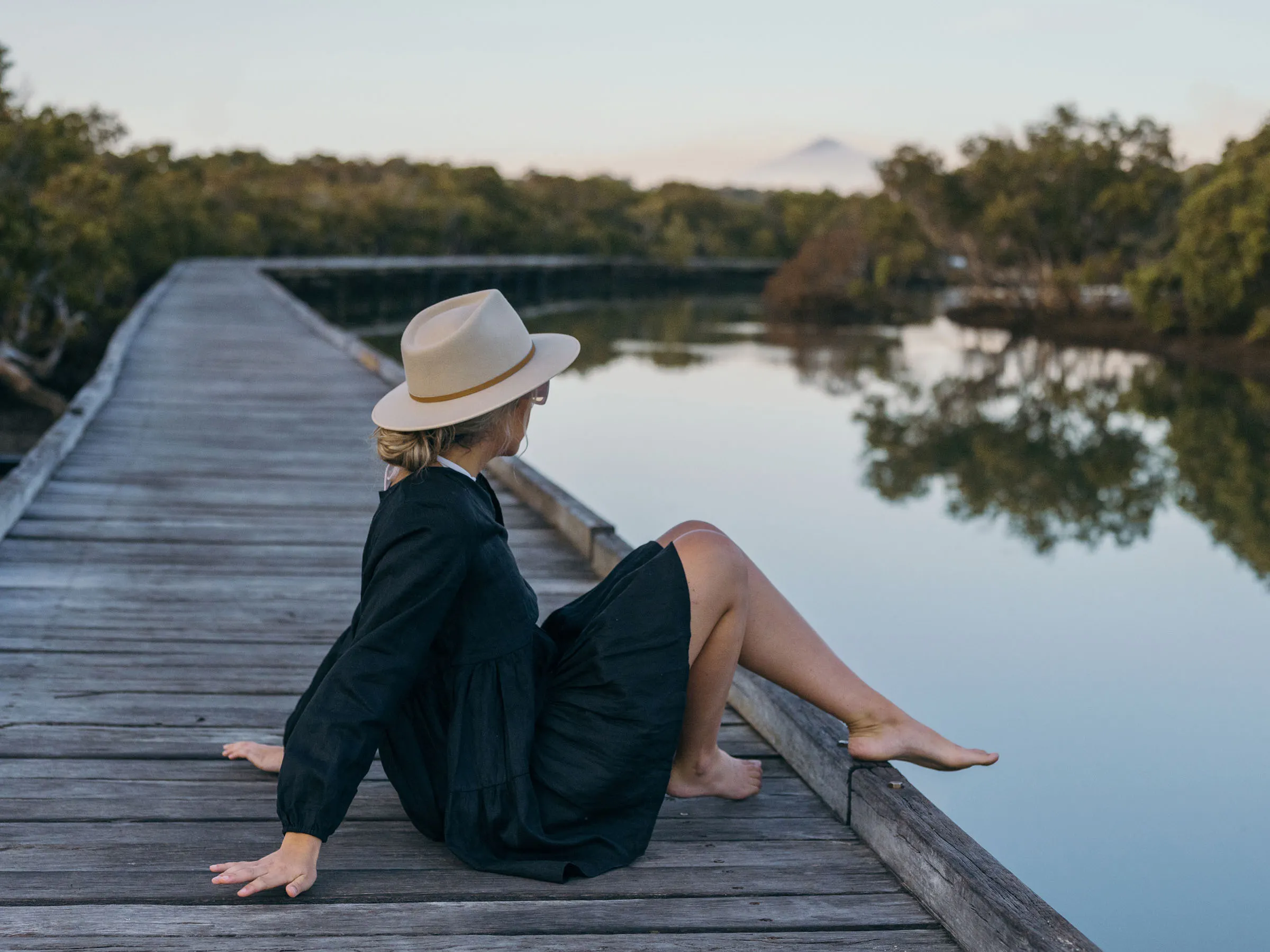 Reflections Urunga holiday and caravan park woman sitting watching sunrise on Urunga boardwalk