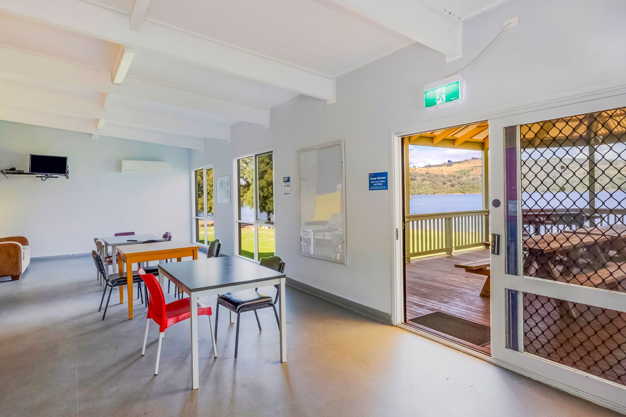 ndoor seating area of the camp kitchen with multiple tables, natural light, and views across the lake