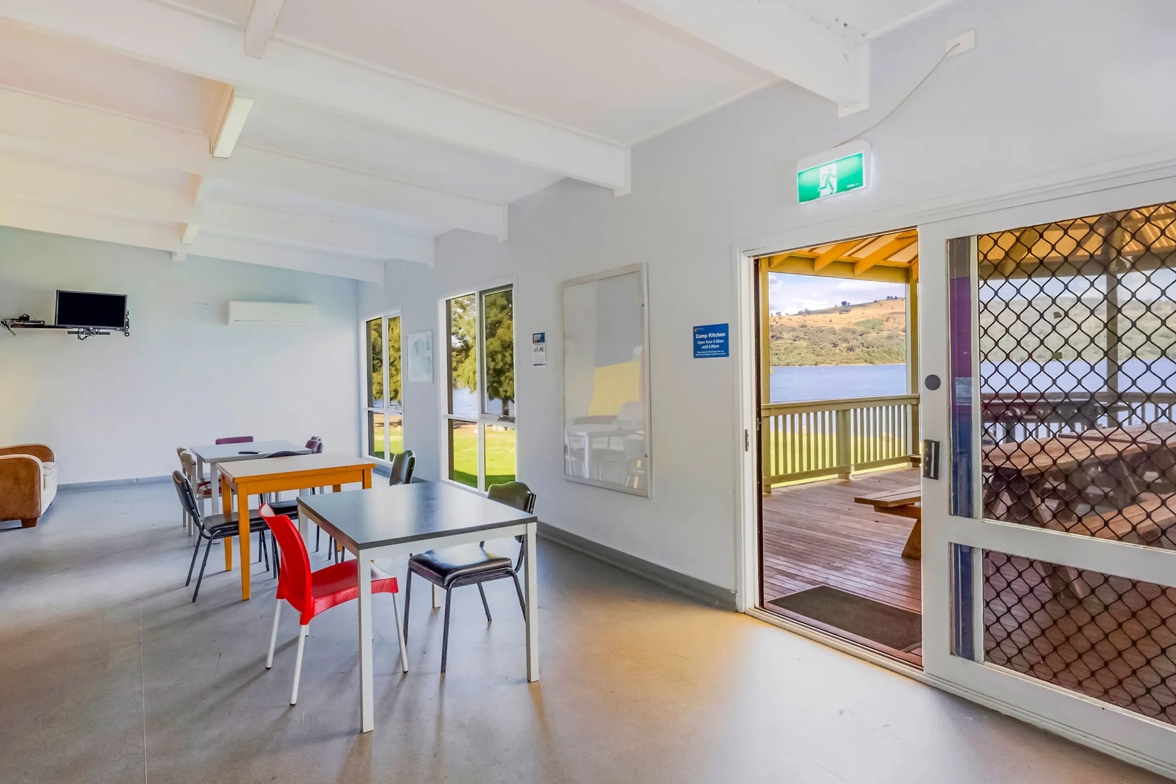 ndoor seating area of the camp kitchen with multiple tables, natural light, and views across the lake