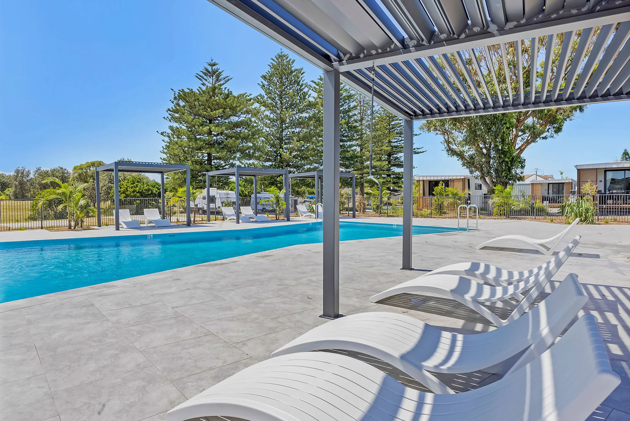 Wide-angle view of the pool at Reflections Hawks Nest, showcasing the surrounding holiday park and lush trees.