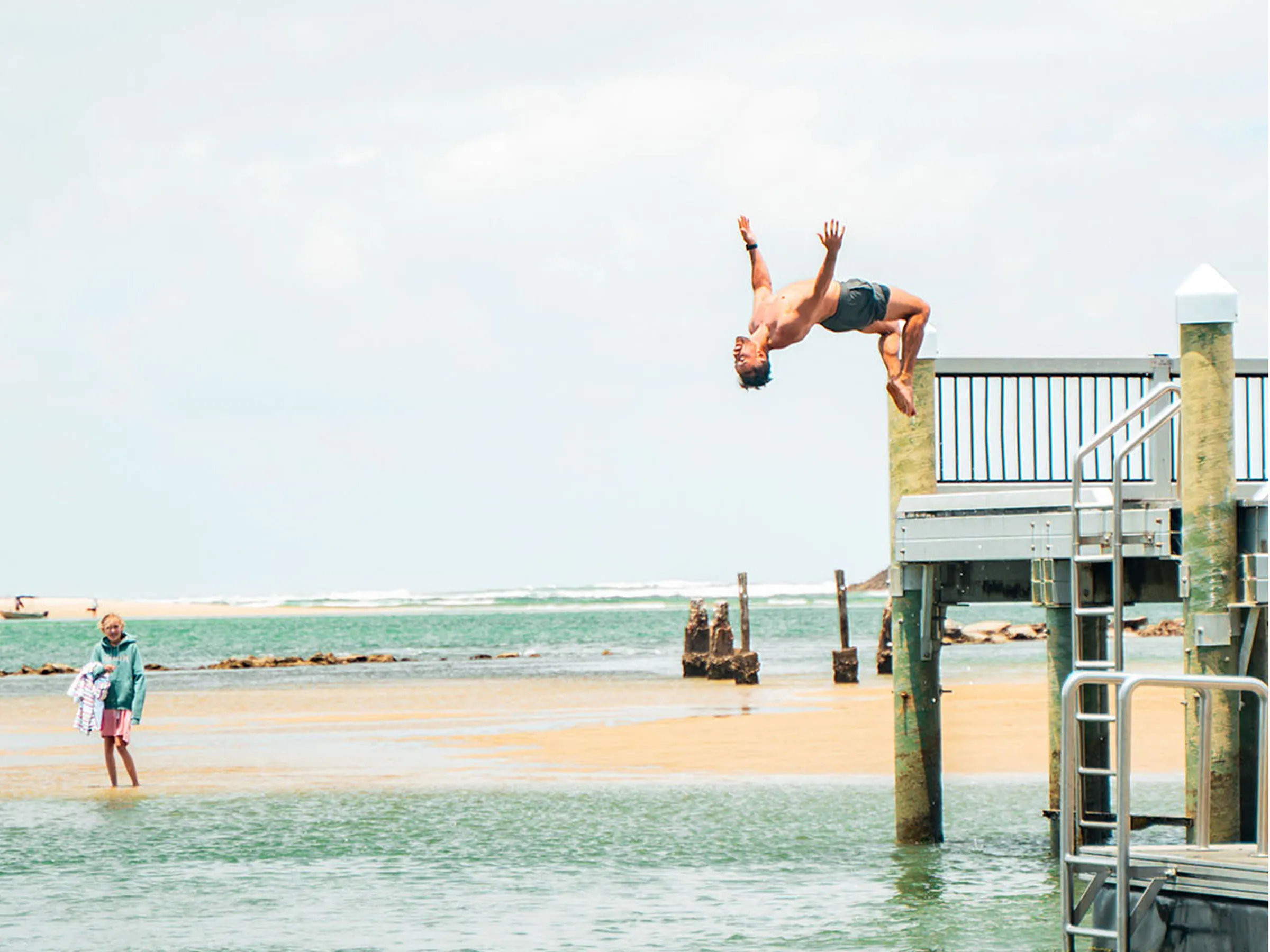 Reflections Urunga holiday and caravan park man backflipping off pier into water