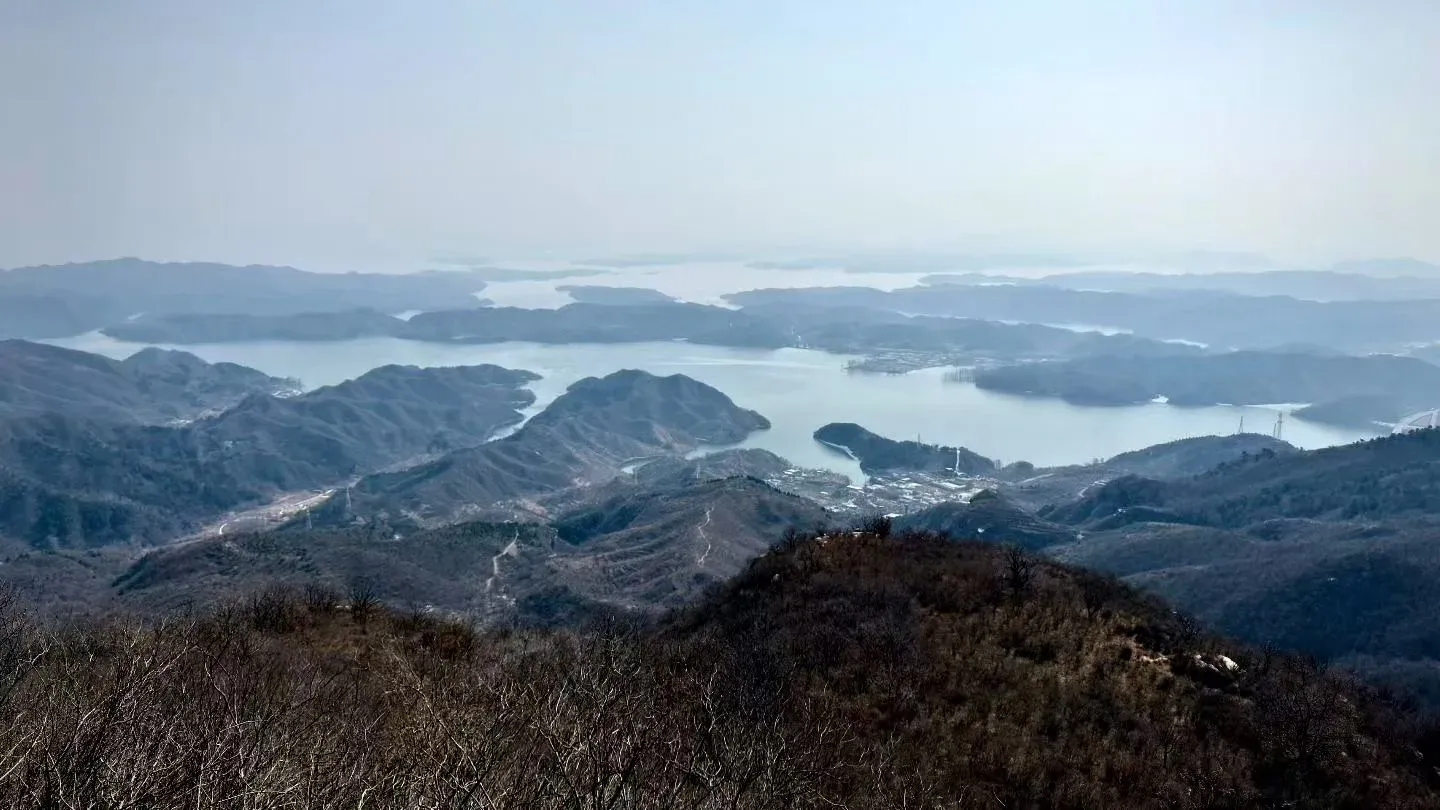 冬日高处俯瞰水库，水面在连绵山谷间反复转折。