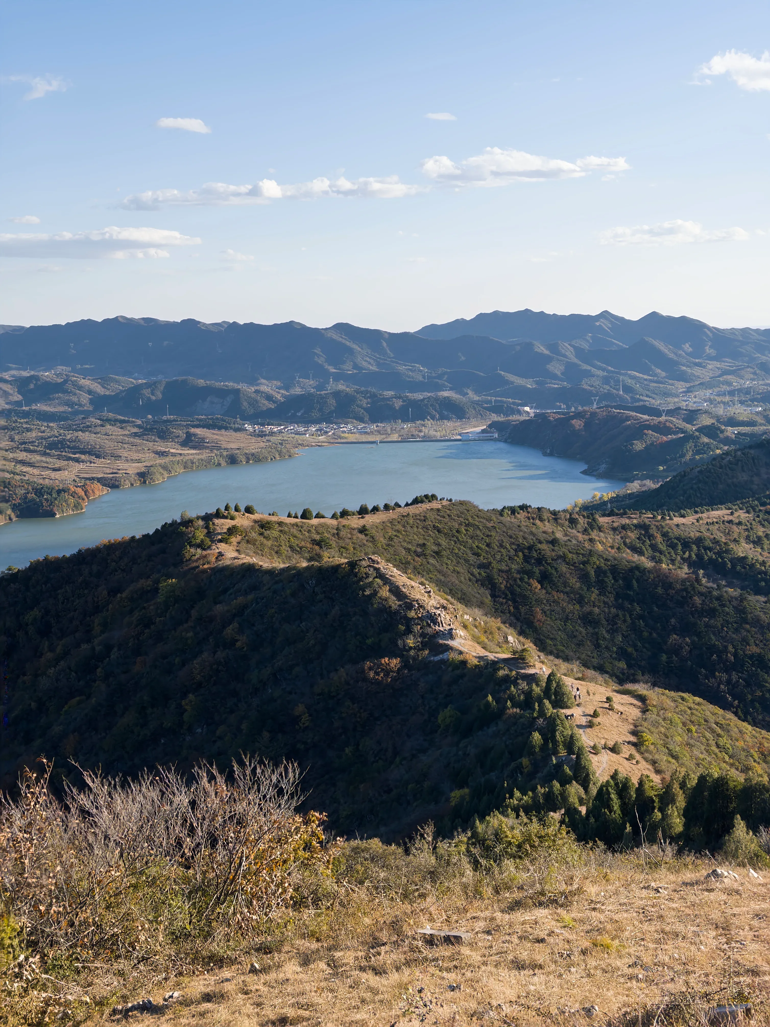 竖幅视角沿城墙回望群山，山谷与水面在脚下展开。