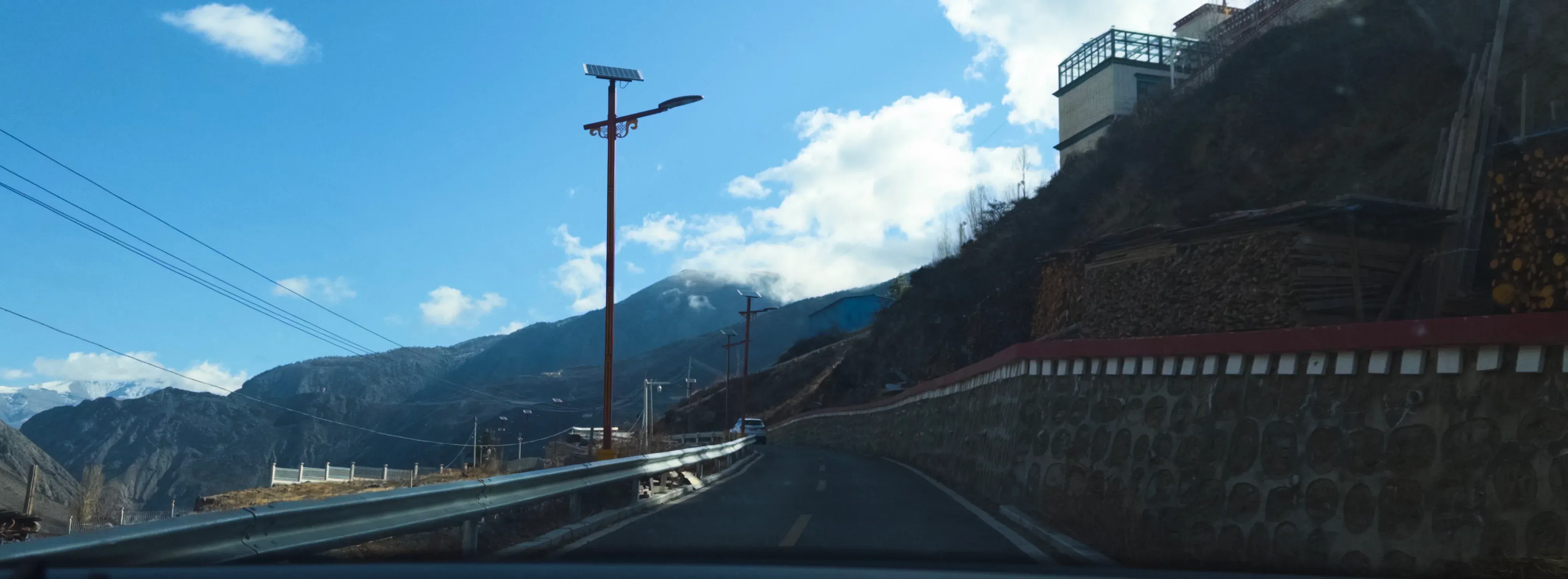 公路穿过高山峡谷，云影和护栏指向明亮的远方。