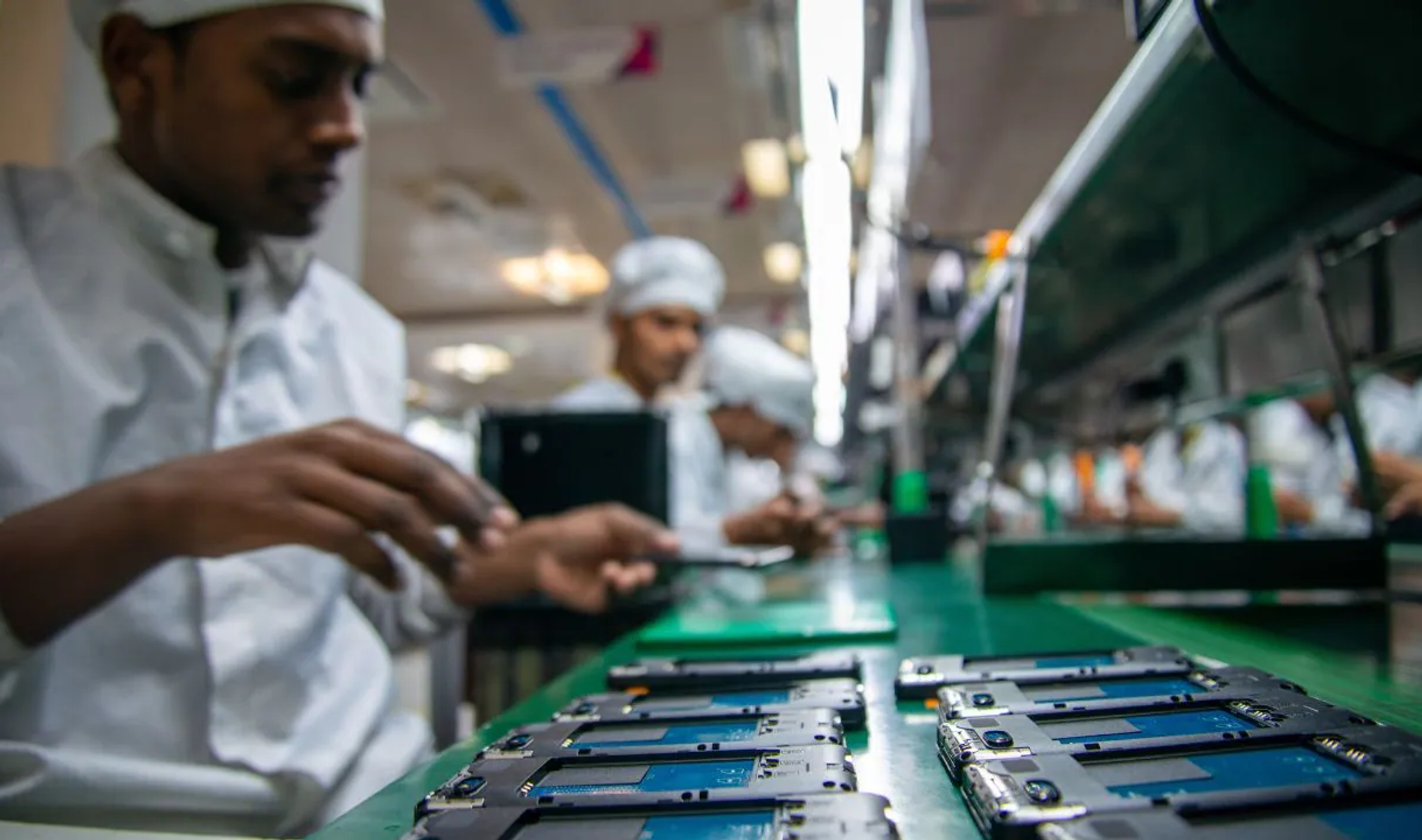 Workers assembling smartphones on a mobile phone production line in India.