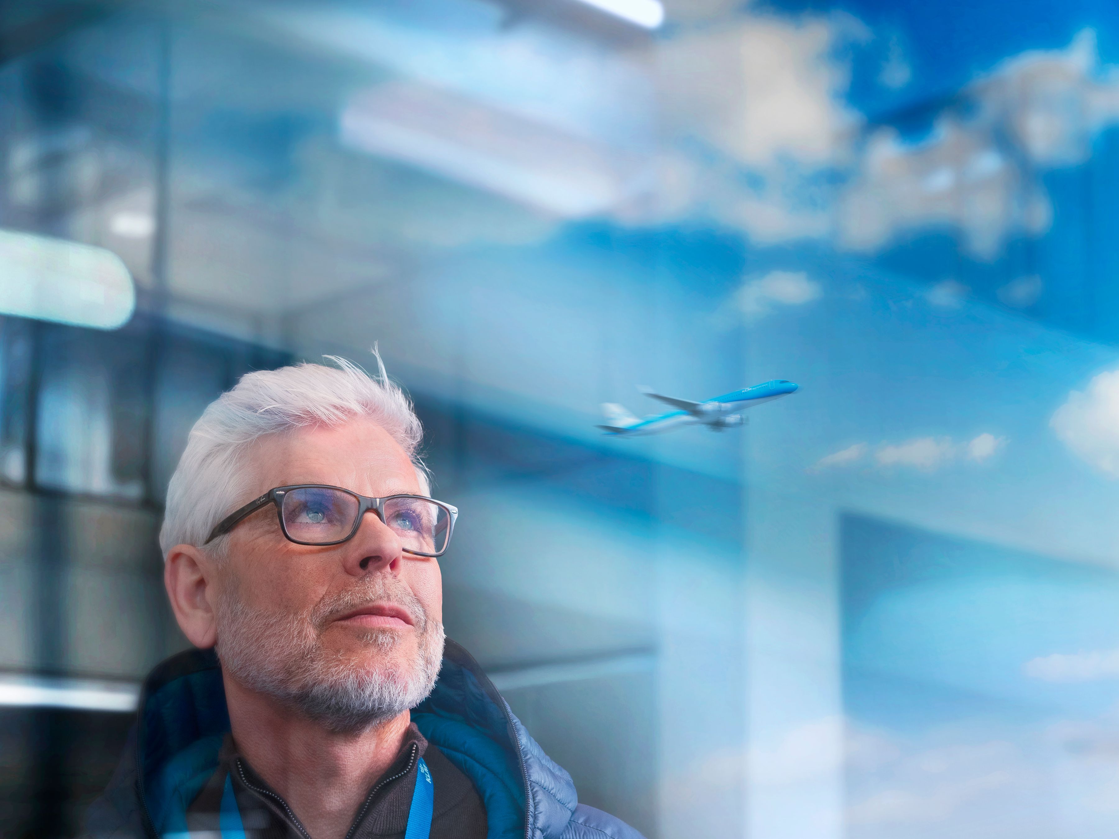 Older male KLM colleague watching a plane depart