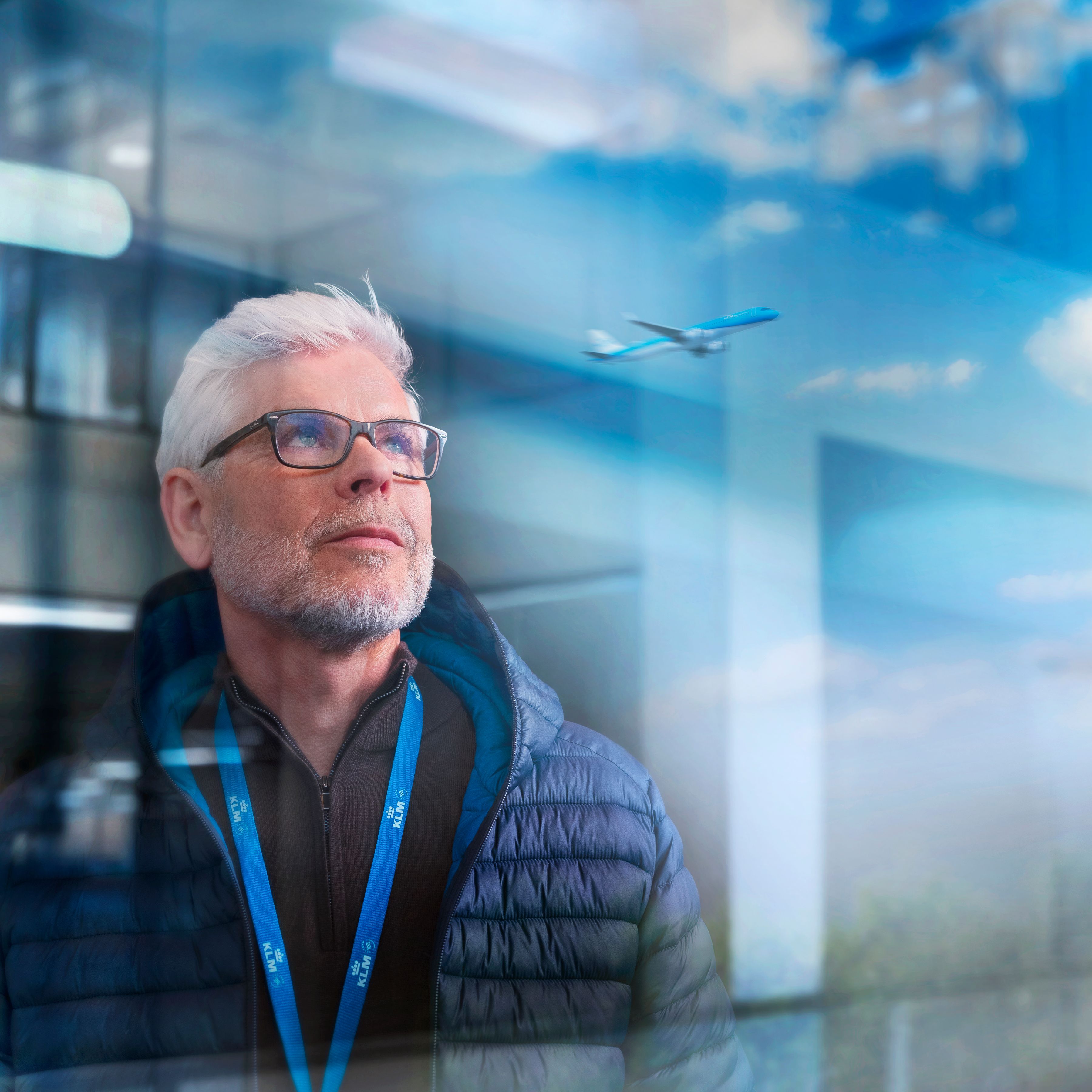 Older male KLM colleague watching a plane depart.