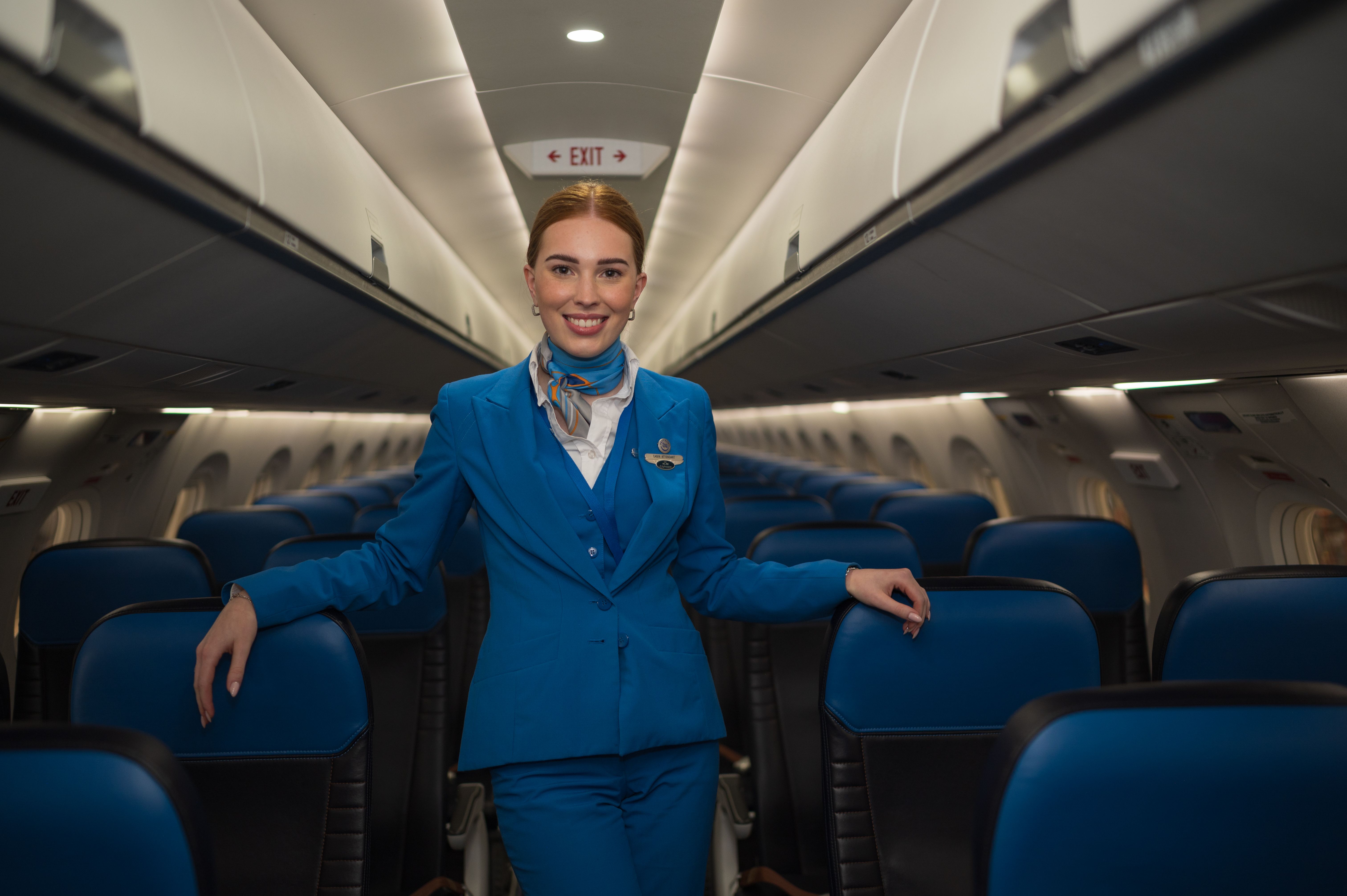 KLM Cityhopper cabin attendant staand in het gangpad van het vliegtuig