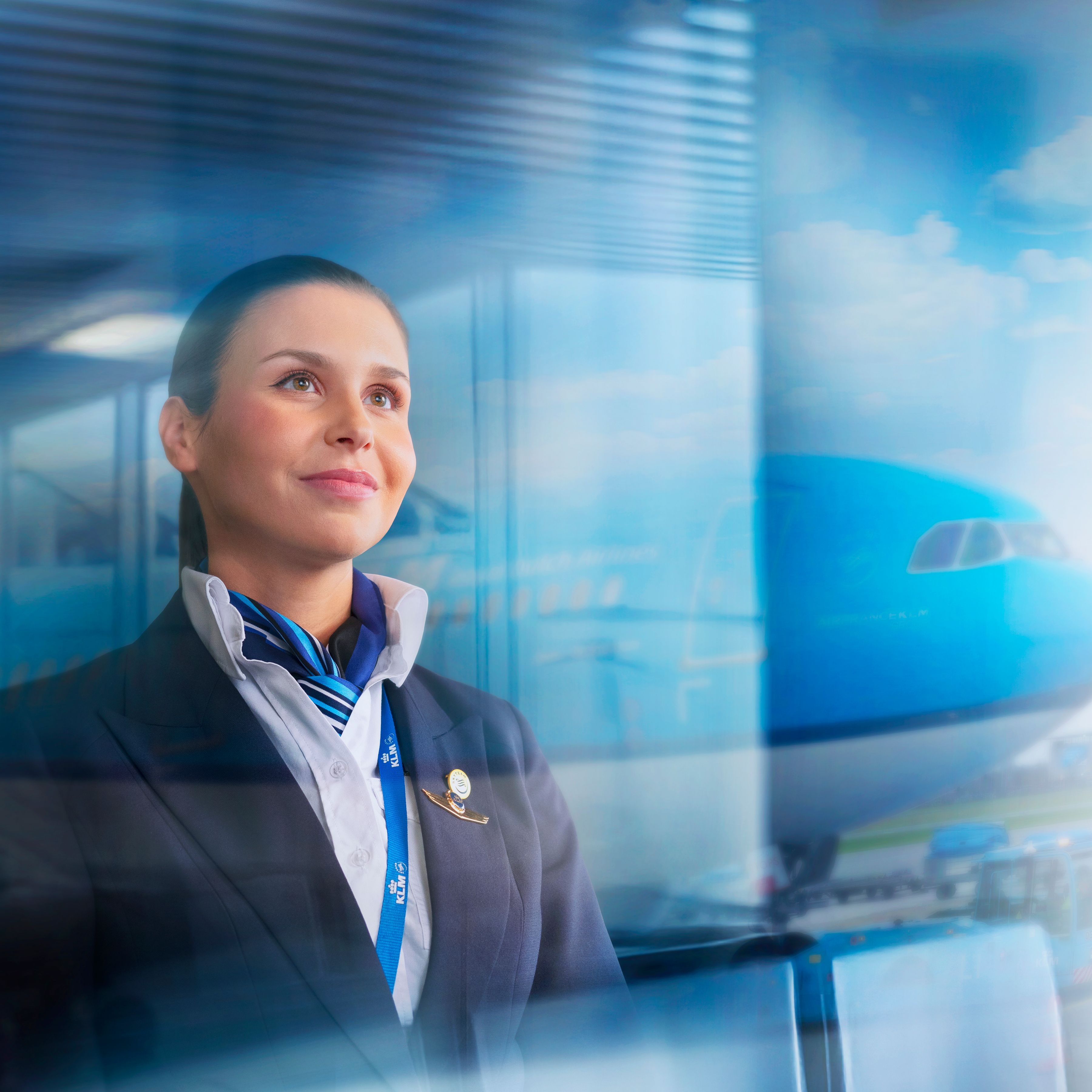 Smiling female pilot looking out of a window with an aircraft in the background