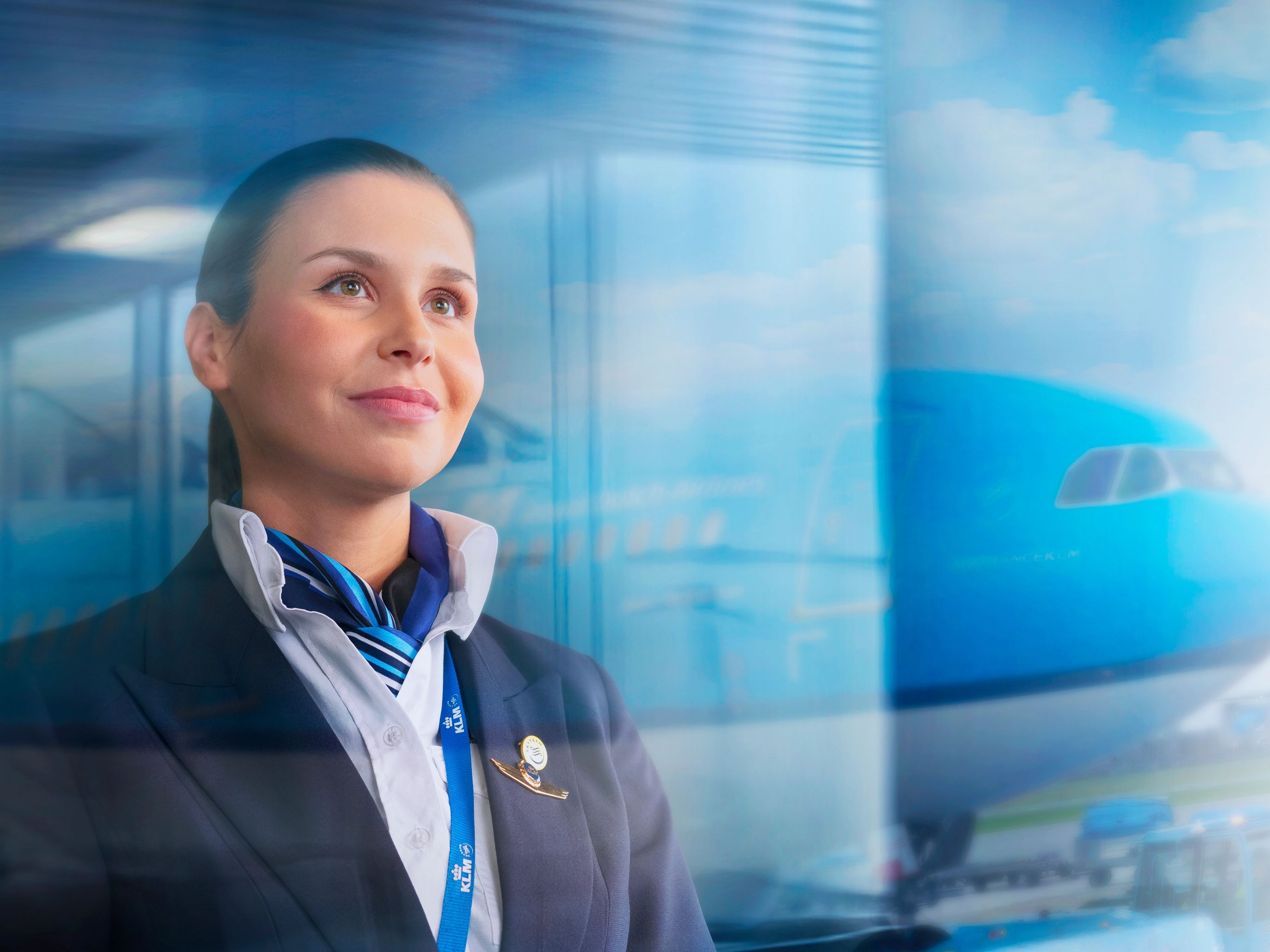 KLM piloot kijkt uit het raam met in de achtergrond een KLM vliegtuig