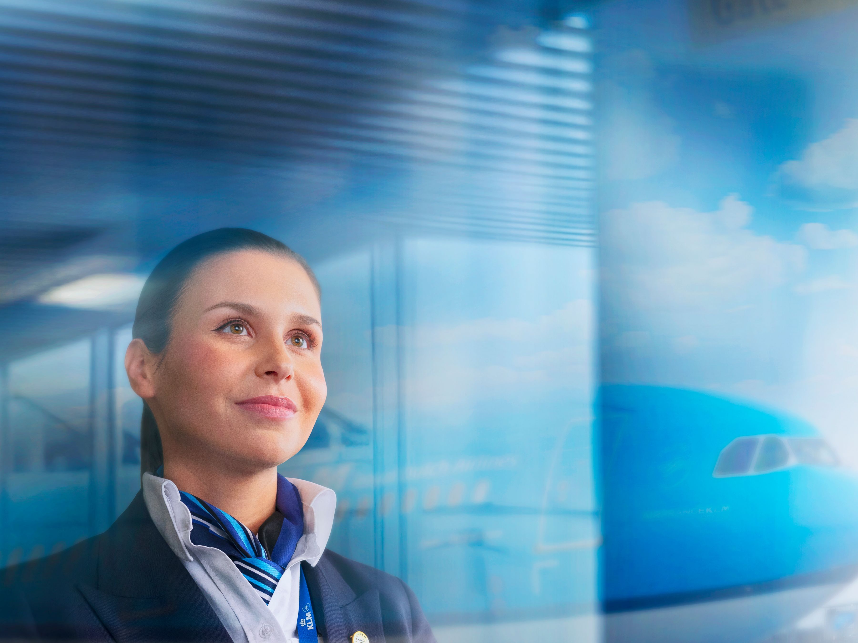 Smiling female pilot looking out of a window with an aircraft in the background