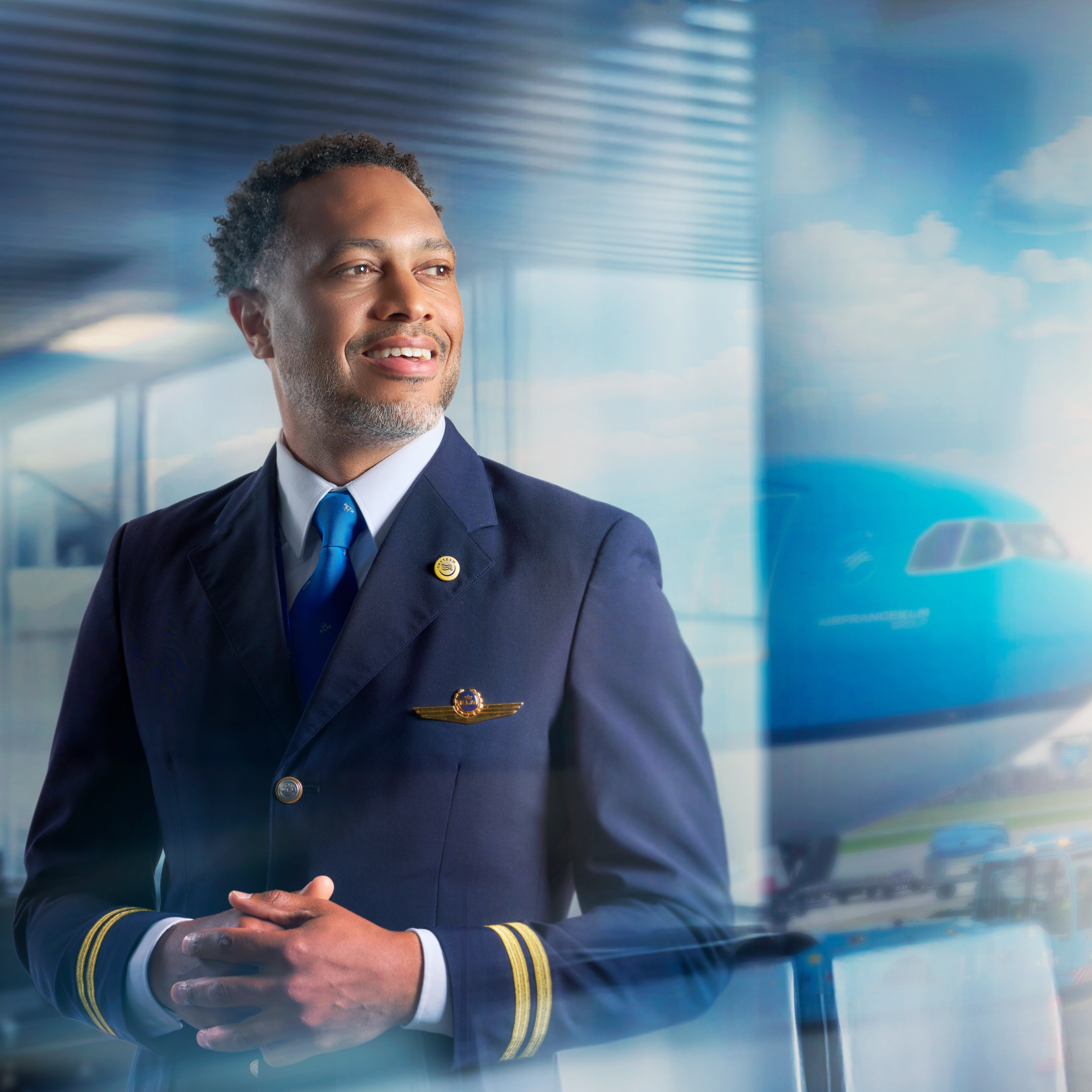 A man in a pilot uniform looking out of the window on the departing plane