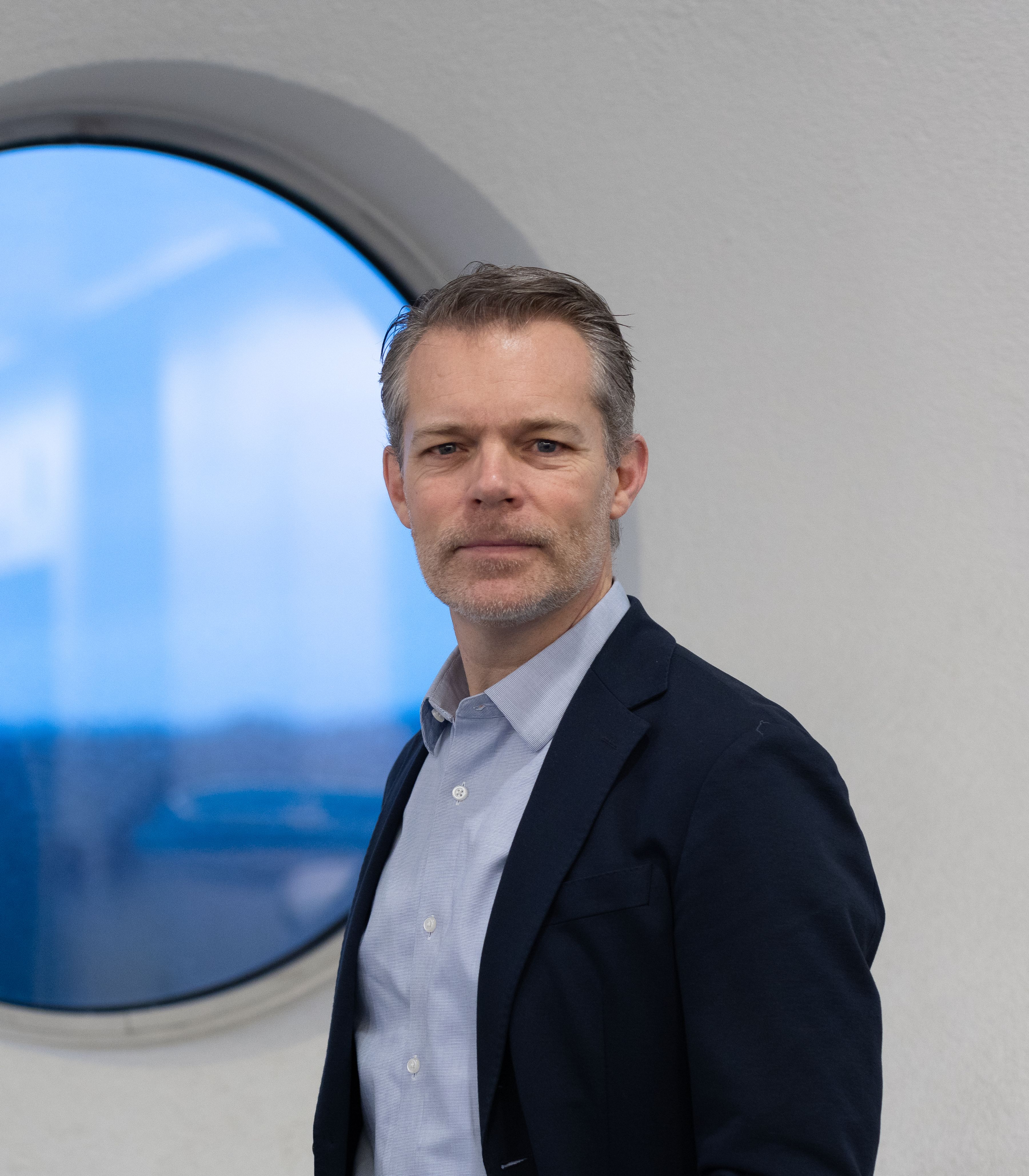 Mannelijke collega van de financële afdeling staat voor een rond raam op de luchthaven