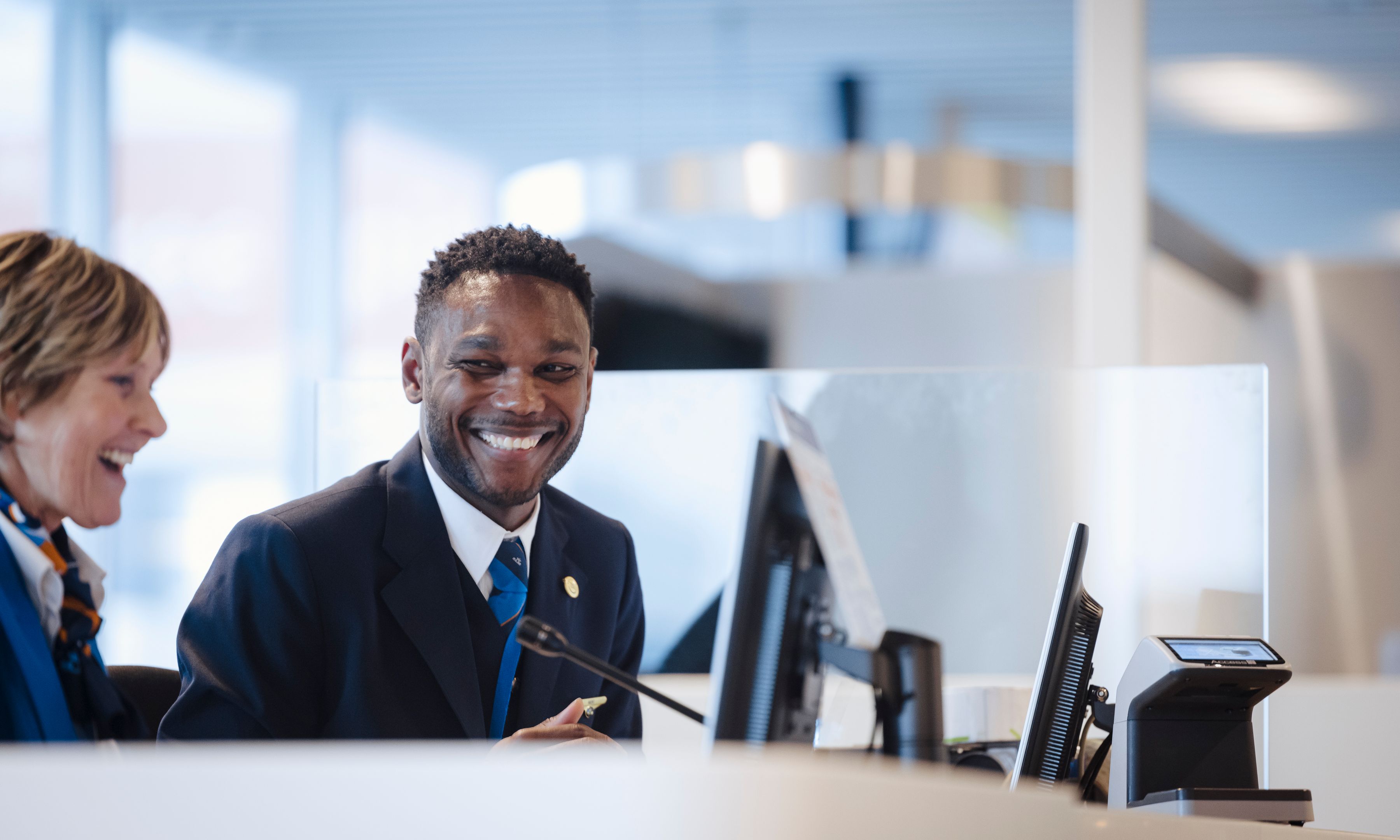 Twee glimlachende gate-medewerkers achter de incheckbalie bij de gate.