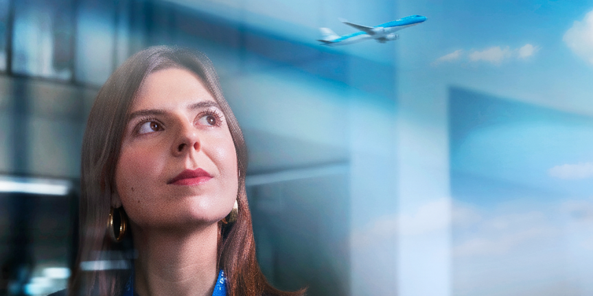 Girl looking up in the sky at departing plane in the reflection on the window