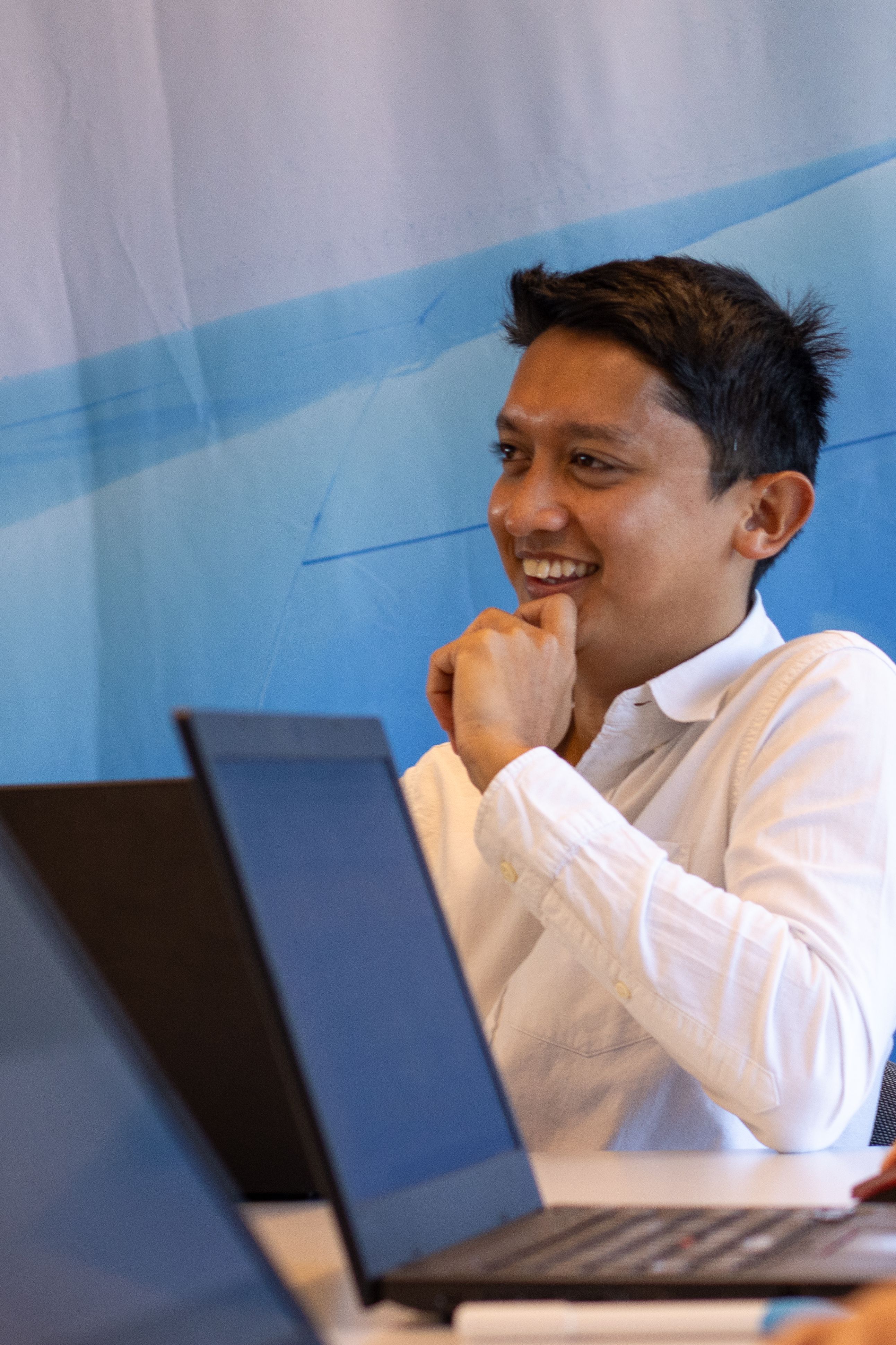 Medewerker met Aziatisch uiterlijk lacht tijdens een vergadering.