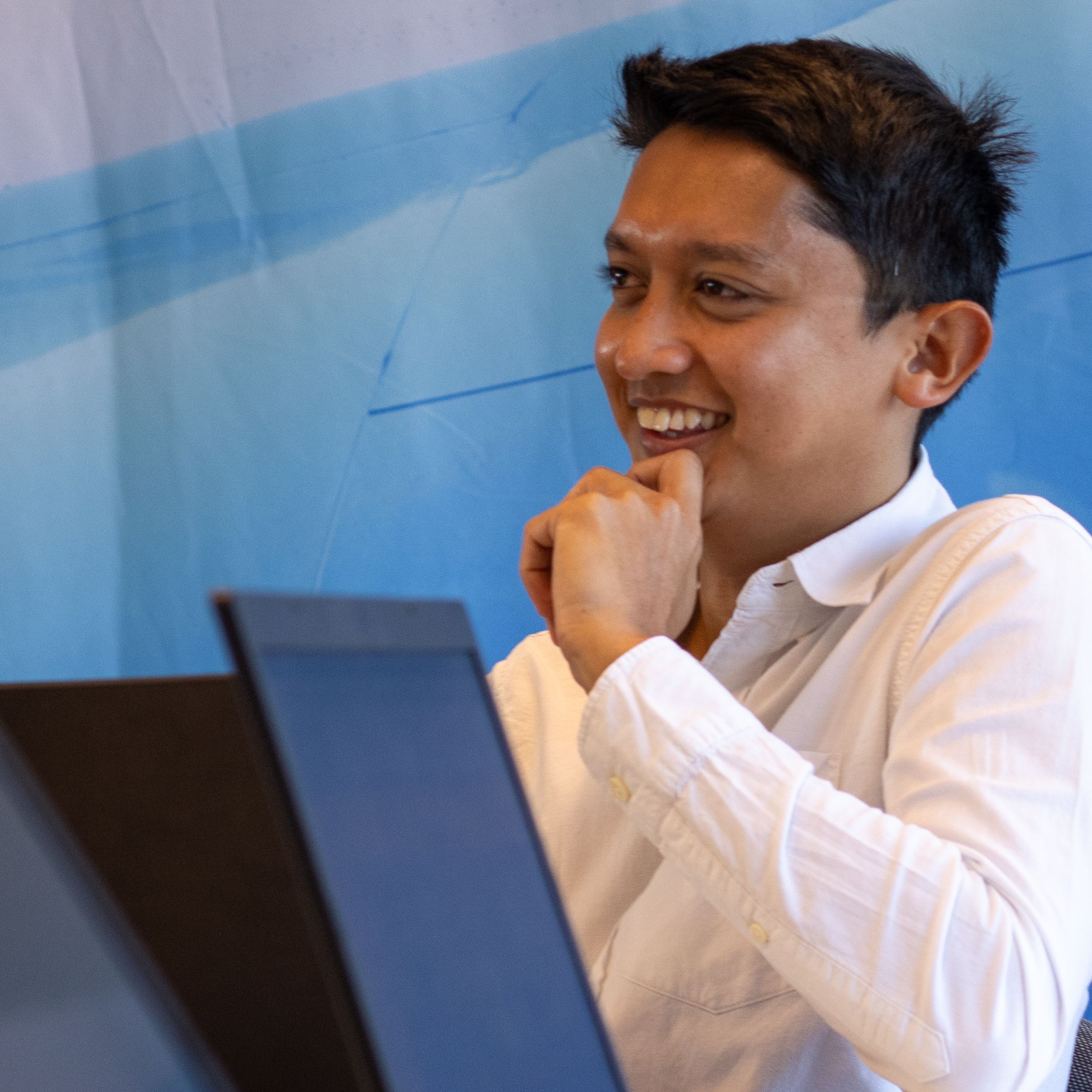 Medewerker met Aziatisch uiterlijk lacht tijdens een vergadering.