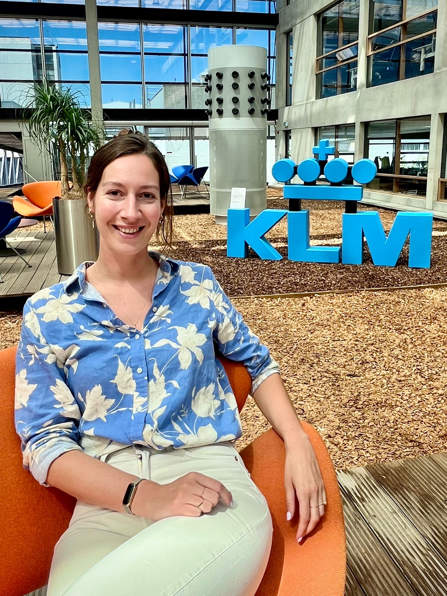 vrouw zit in een stoel voor een klm logo
