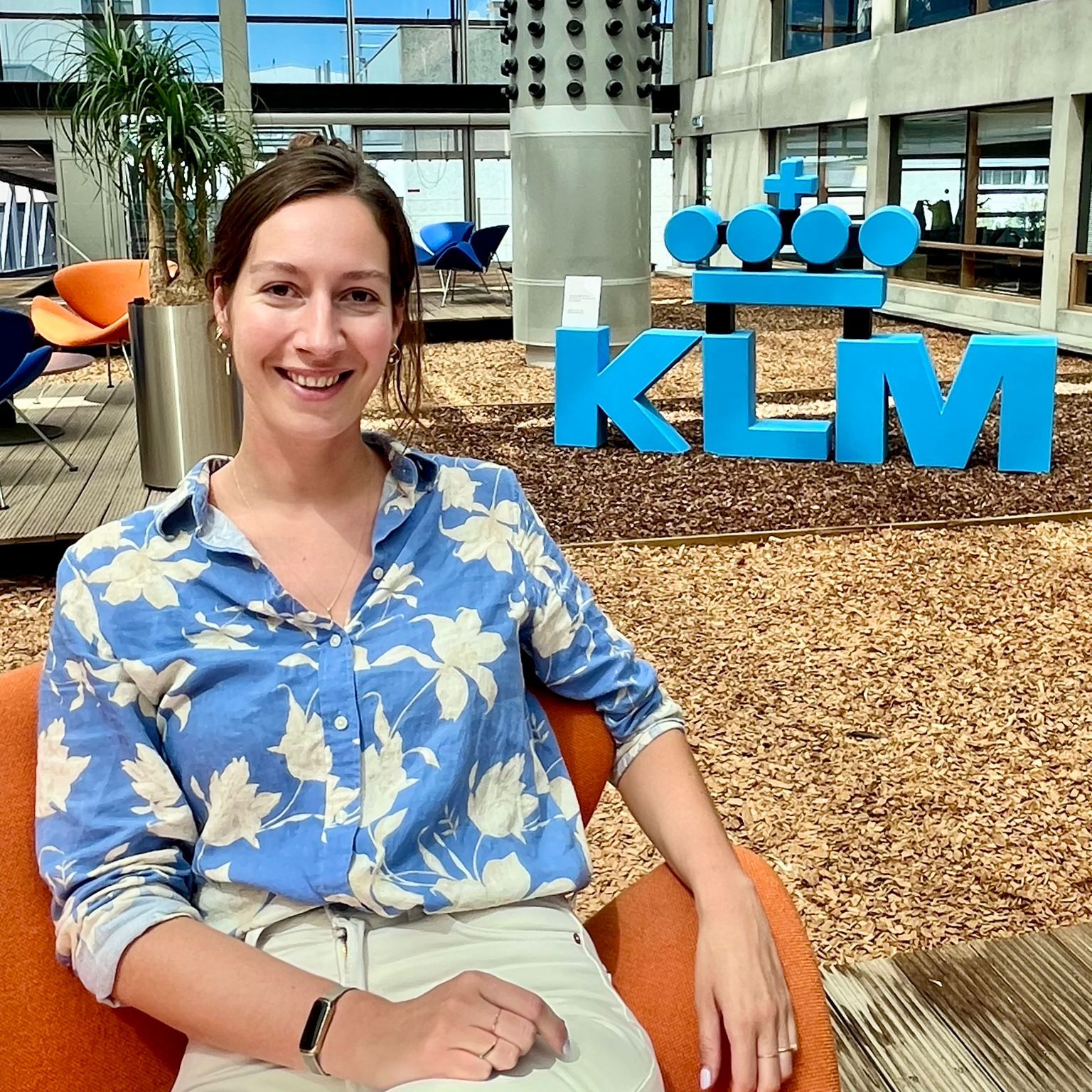 vrouw zit in een stoel voor een klm logo