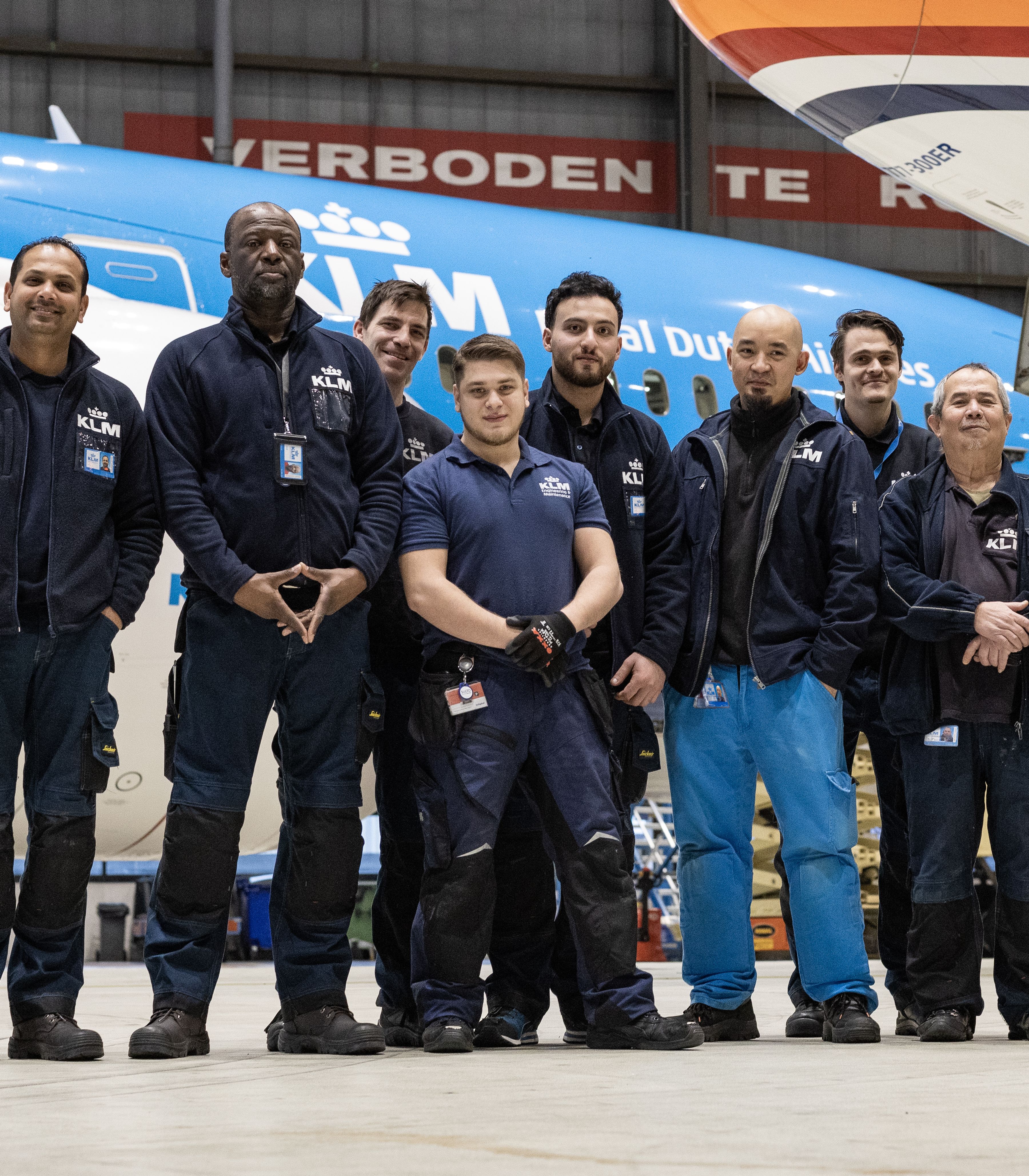 Groepsfoto van een vliegtuigonderhoudsteam staand voor een KLM-vliegtuig in een hangar