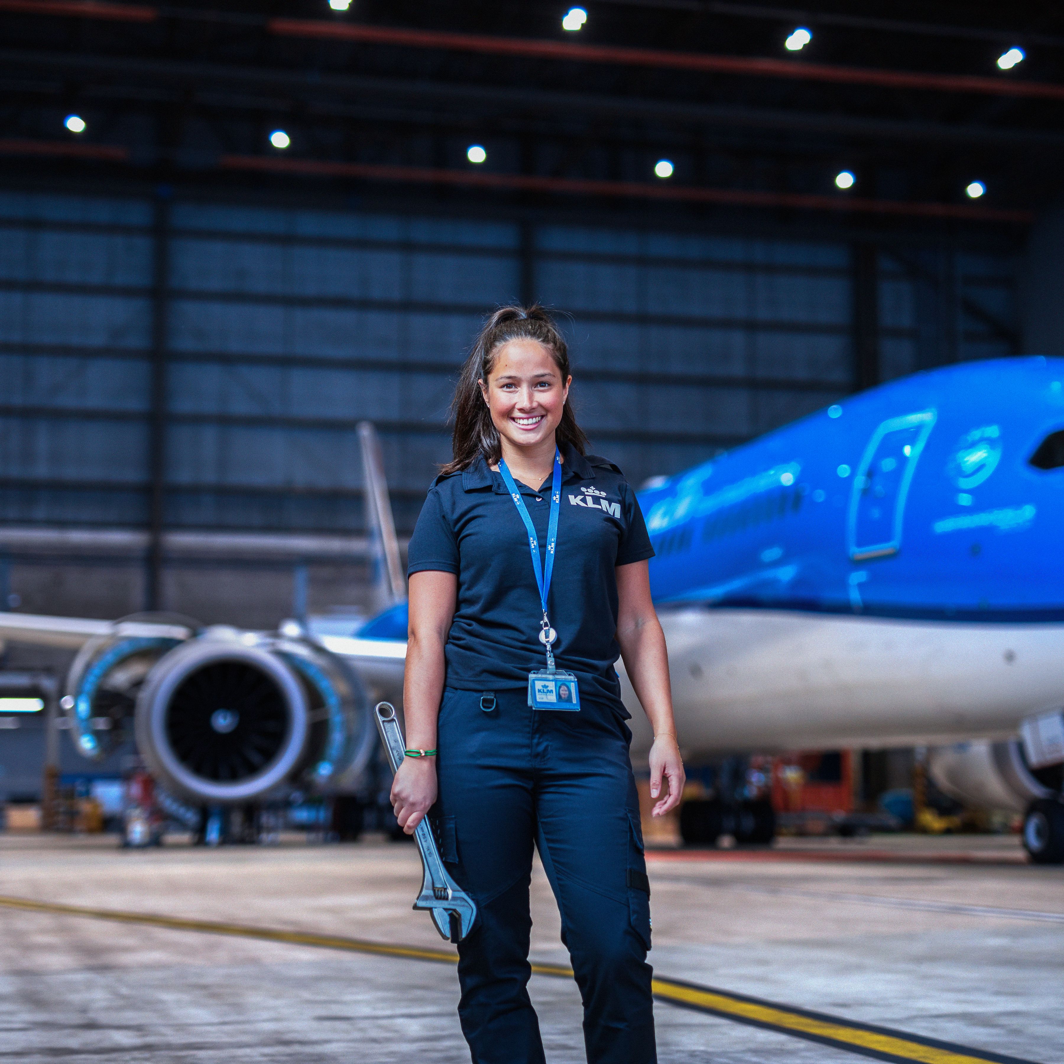 Engineering & Maintenance colleague standing in front on an aircraft in the hanger with a big tool in her hand