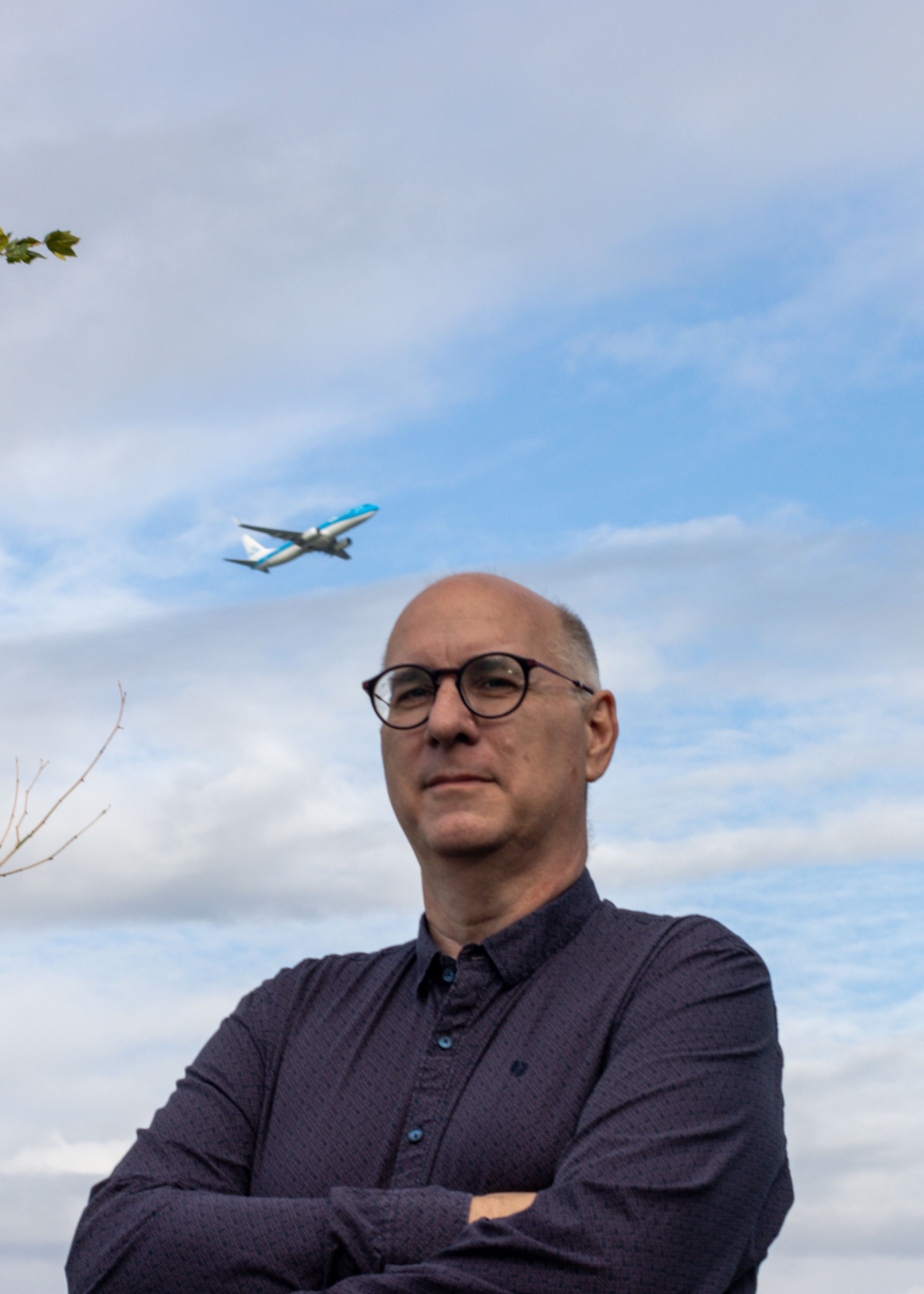 KLM professional standing outside with a departing airplane on the background